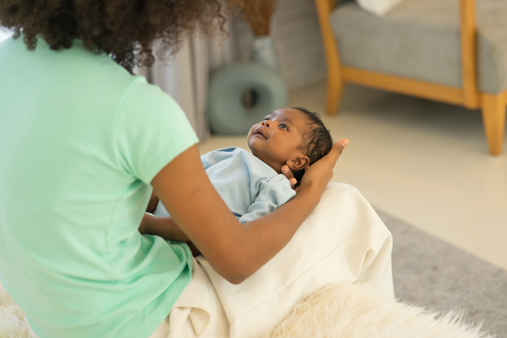 Mother African American holding one-month-old newborn baby gently.