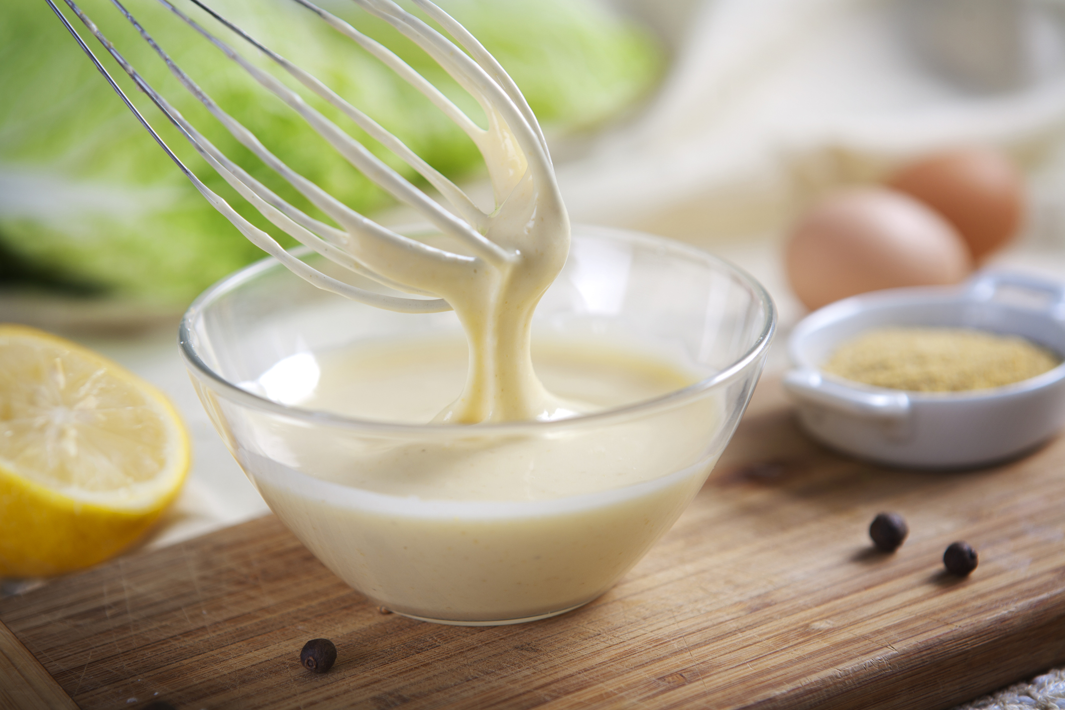 Homemade mayonnaise being whipped in a glass bowl