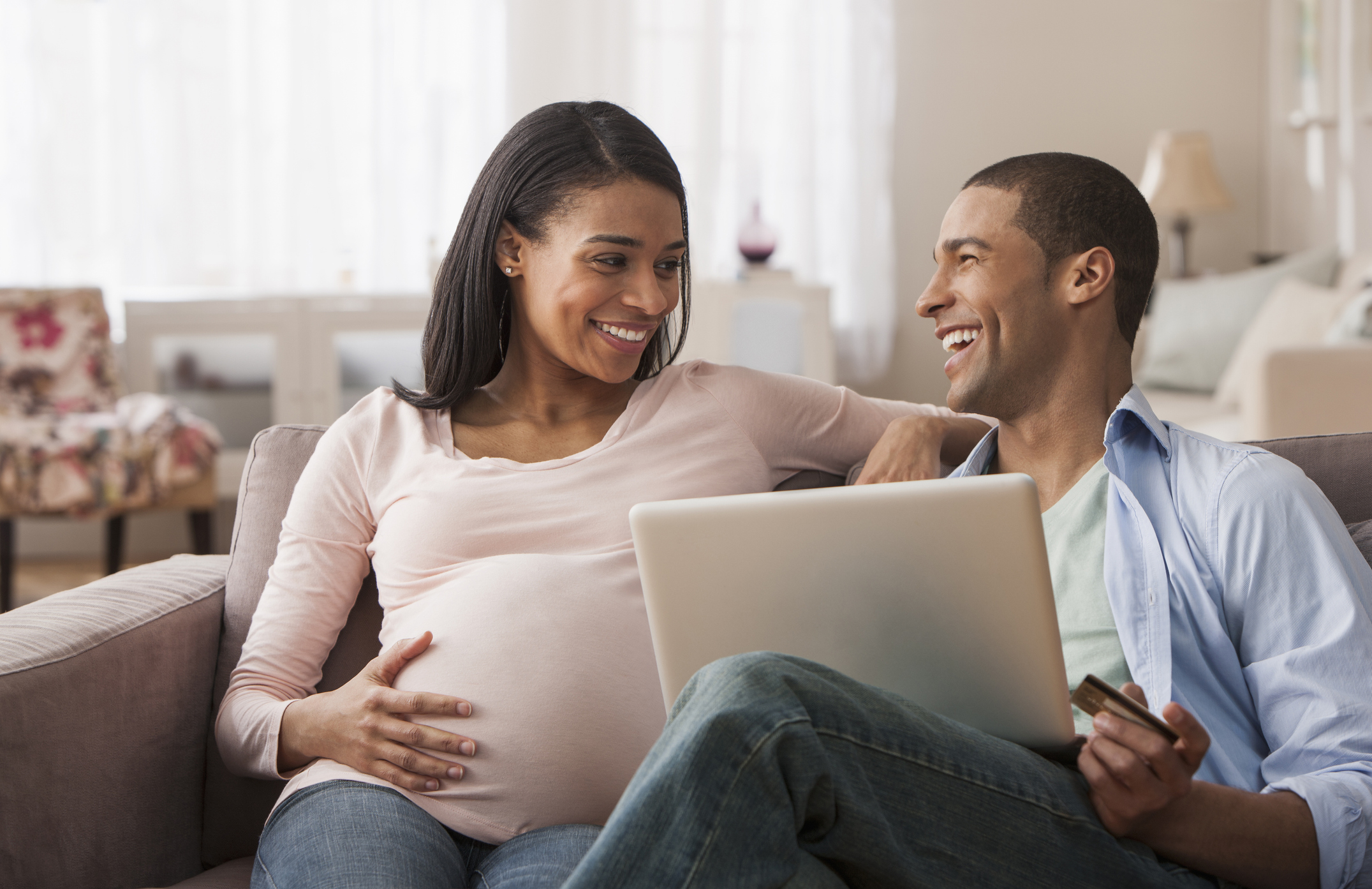 Young pregnant woman sitting with husband and laptop