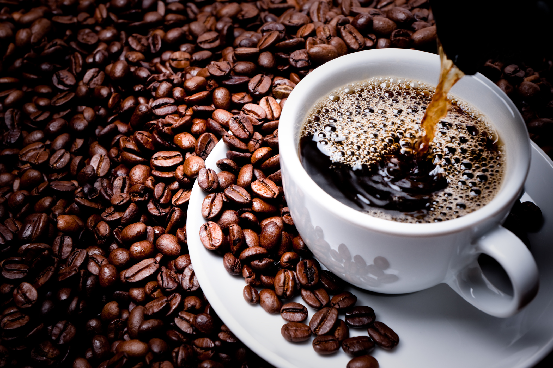 Mug on plate filled with coffee surrounded by coffee beans