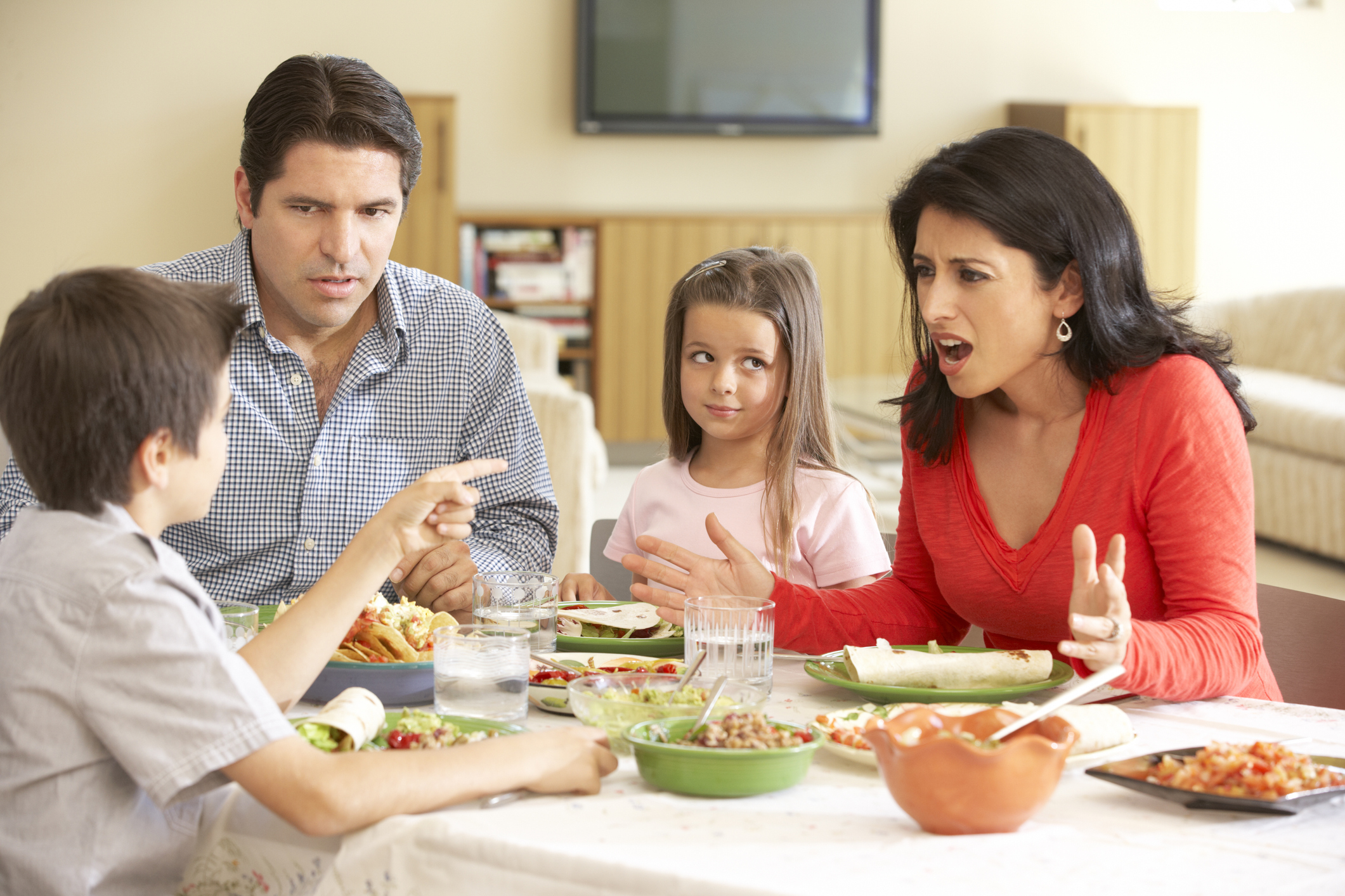 Young Hispanic Family Arguing While Eating Meal At Home