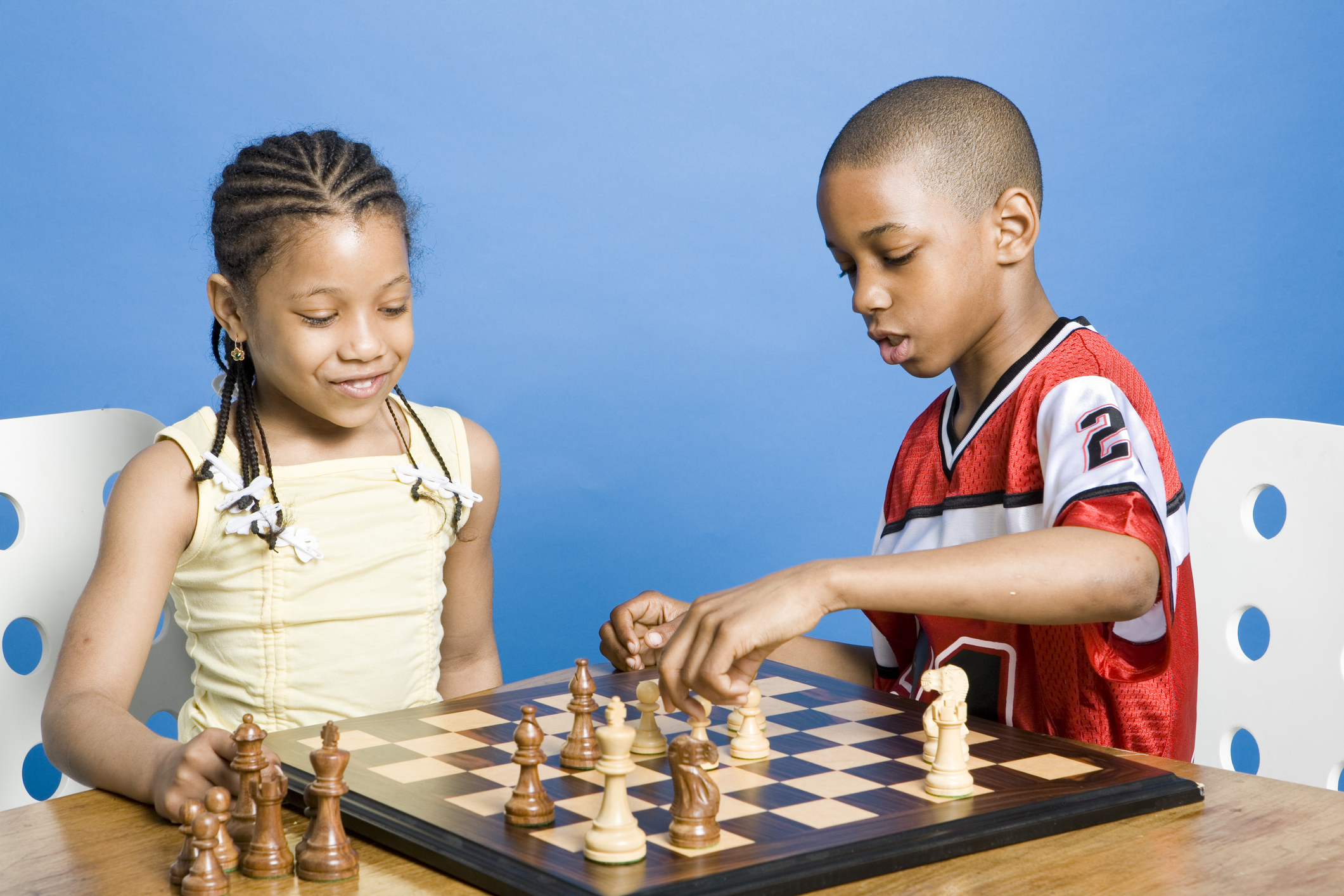 A young girl and boy playing a game of chess