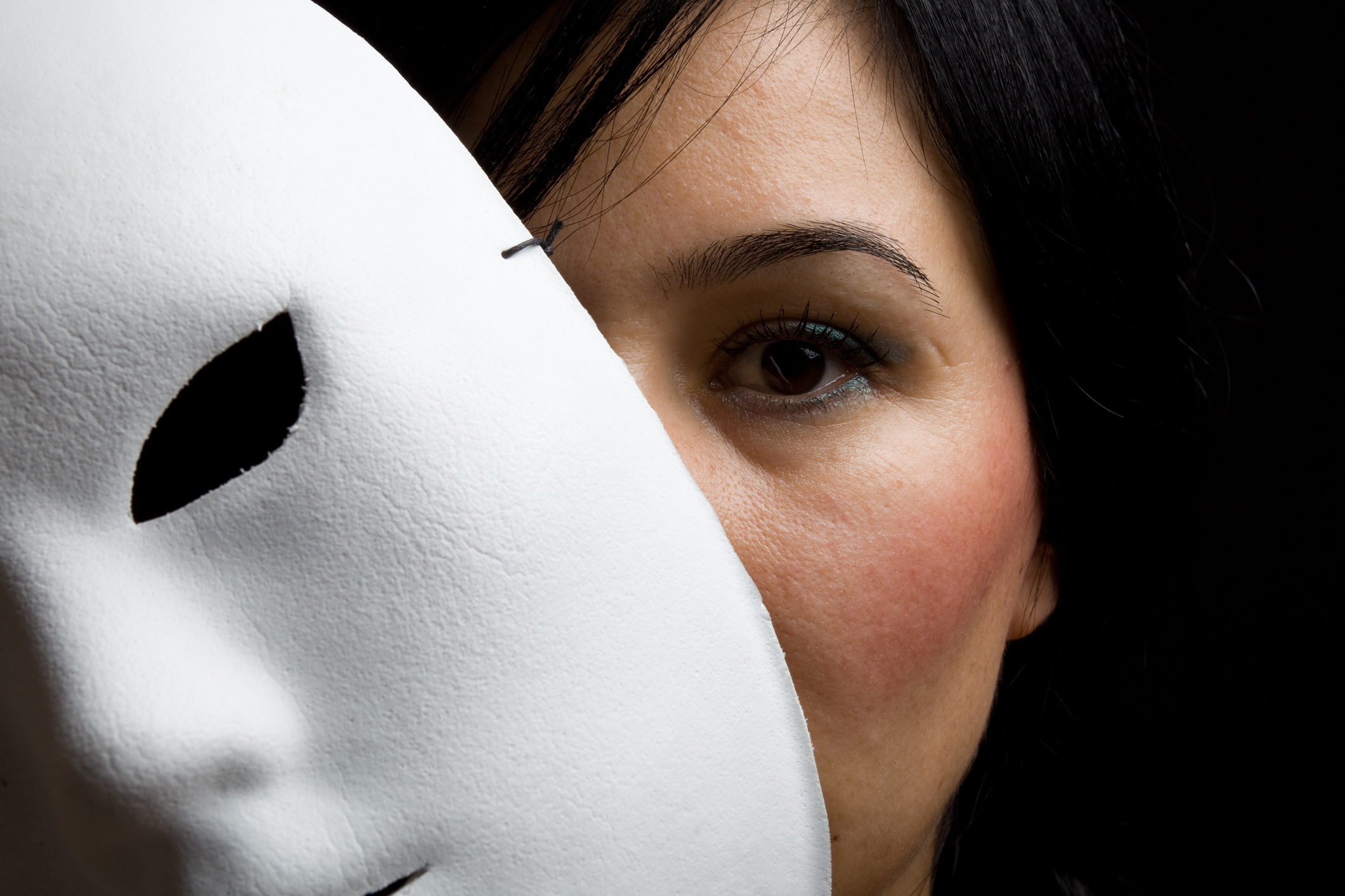 Woman With Black Hair And Eyes Peeking Behind White Mask