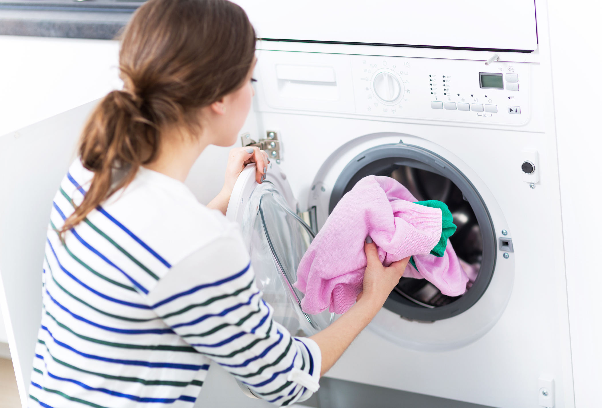 Woman Putting her Laundry into a Washing Machine