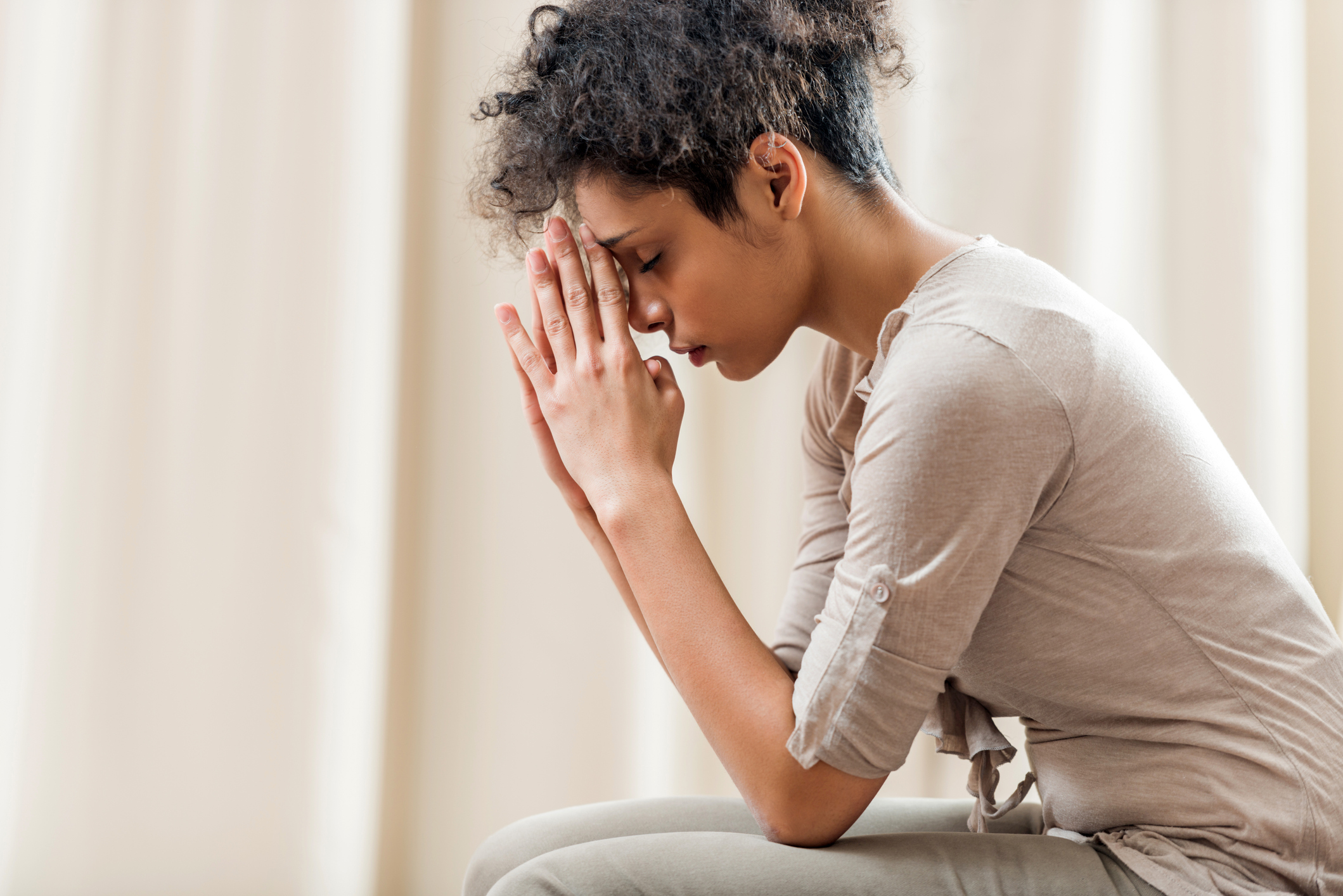 African American woman praying at home.