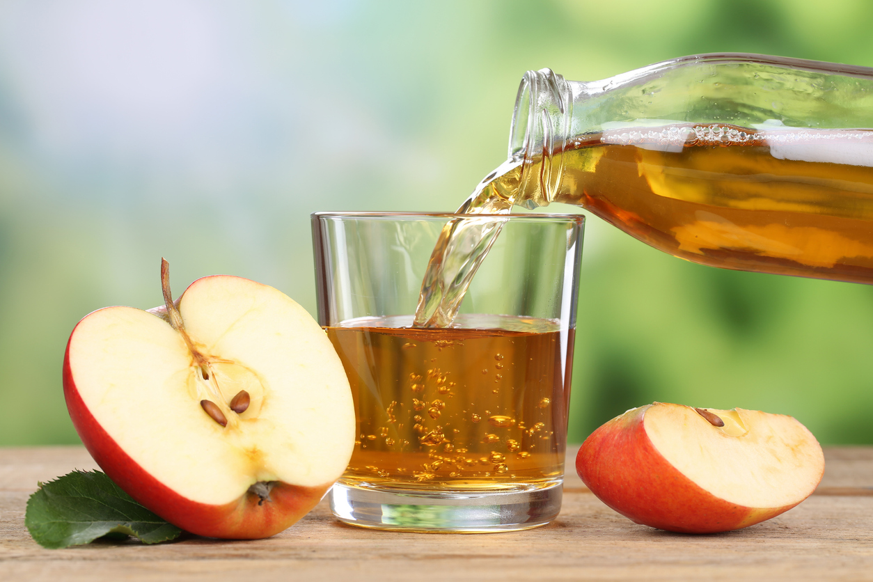 Apple juice pouring from red apples into a glass