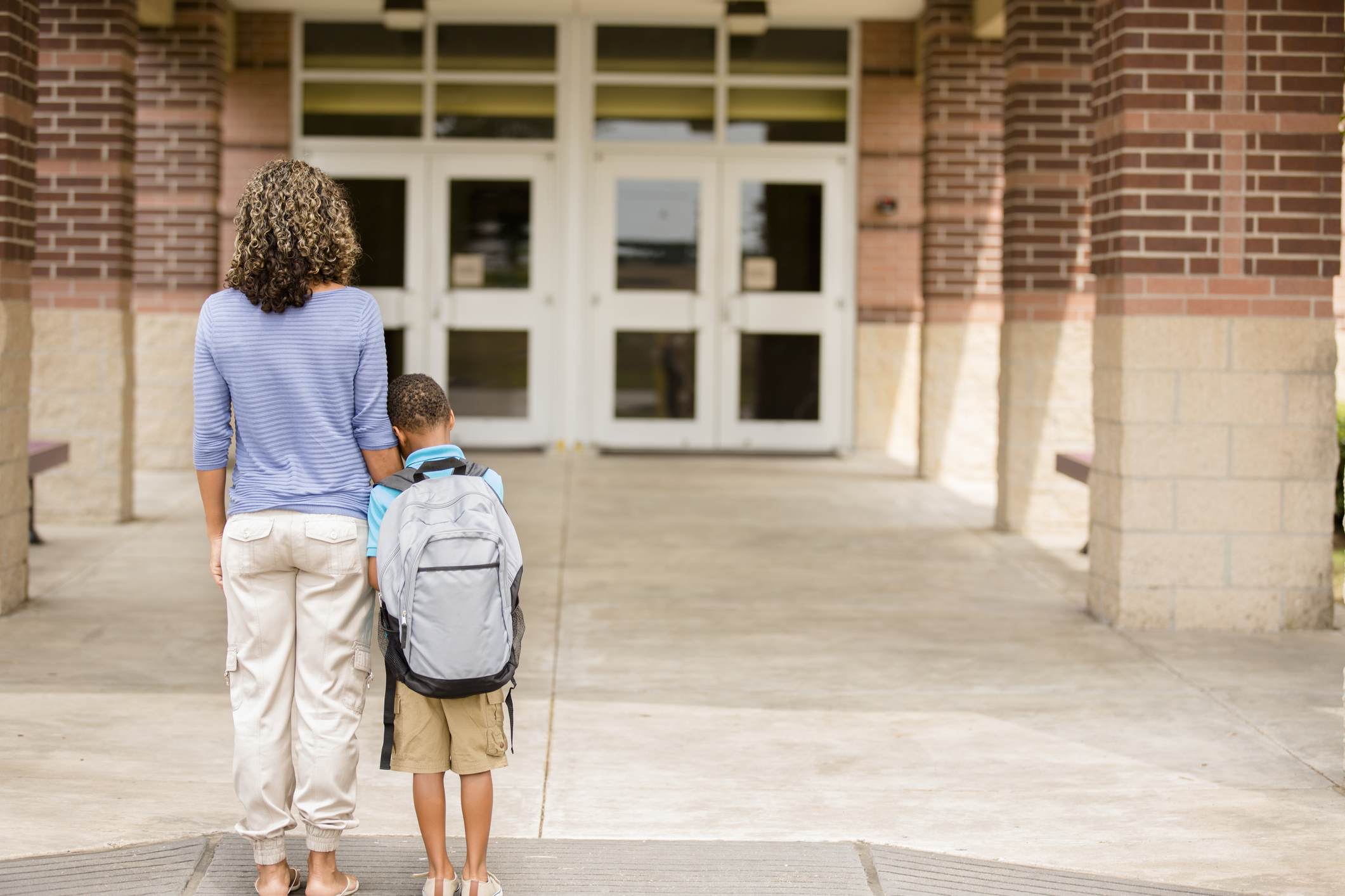 Nervous boy. First day of school.  Holds on to mom.