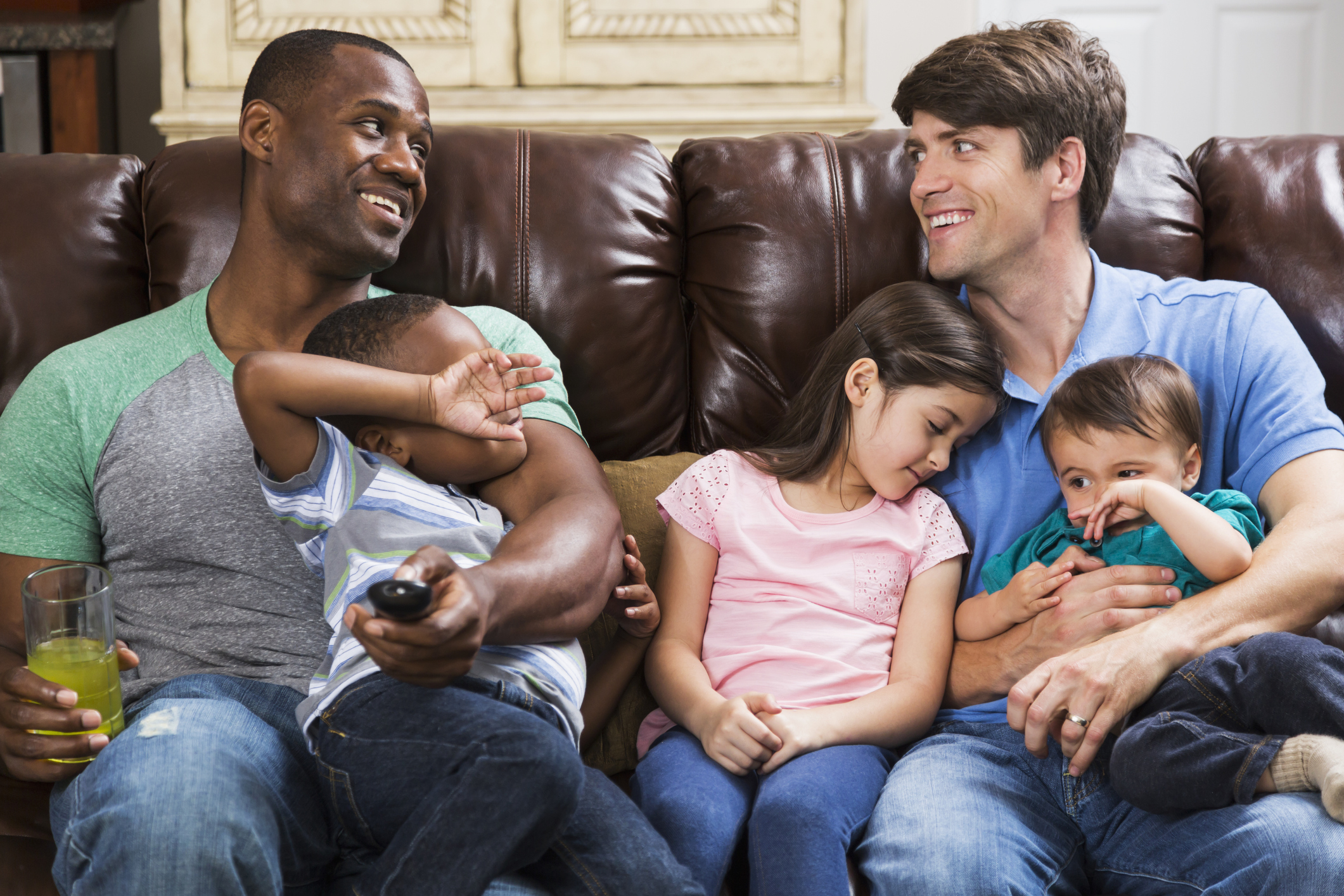 Multi-ethnic fathers with children on couch watching TV