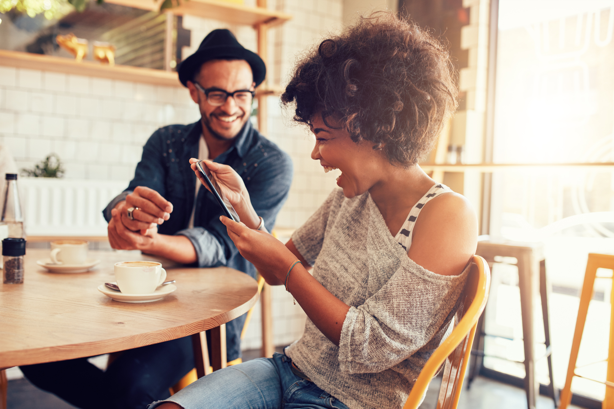 Cheerful woman using digital tablet with a friend at cafe