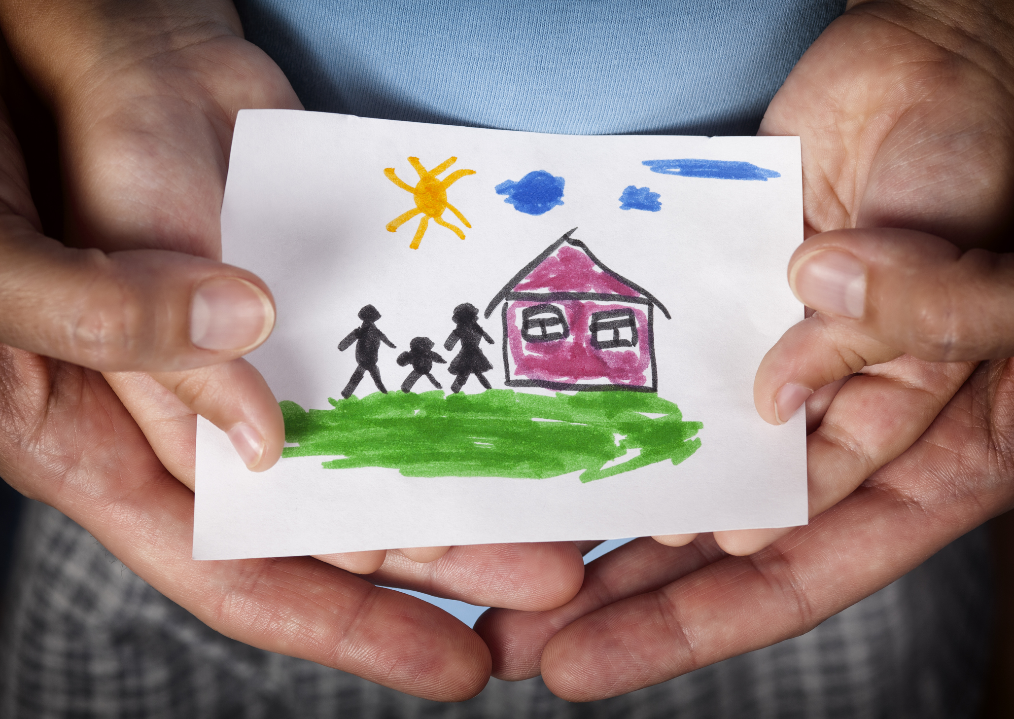 Child and his mom holding a drawn house with family