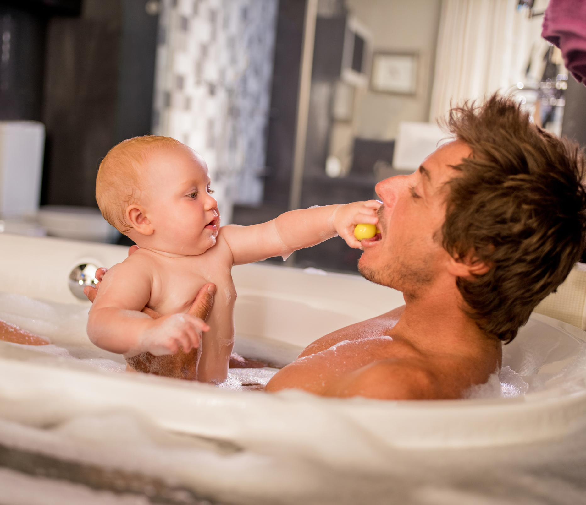 Modern Dad Taking Bubble Bath with Infant Daughter