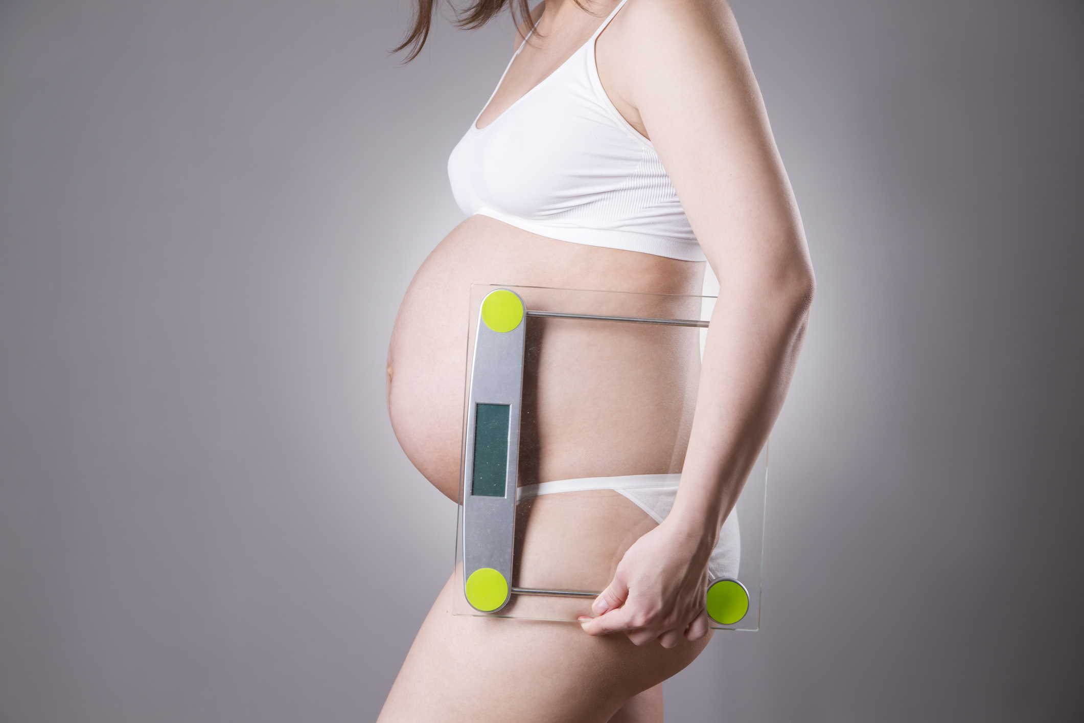 Young caucasian pregnant woman holding in hands the scales