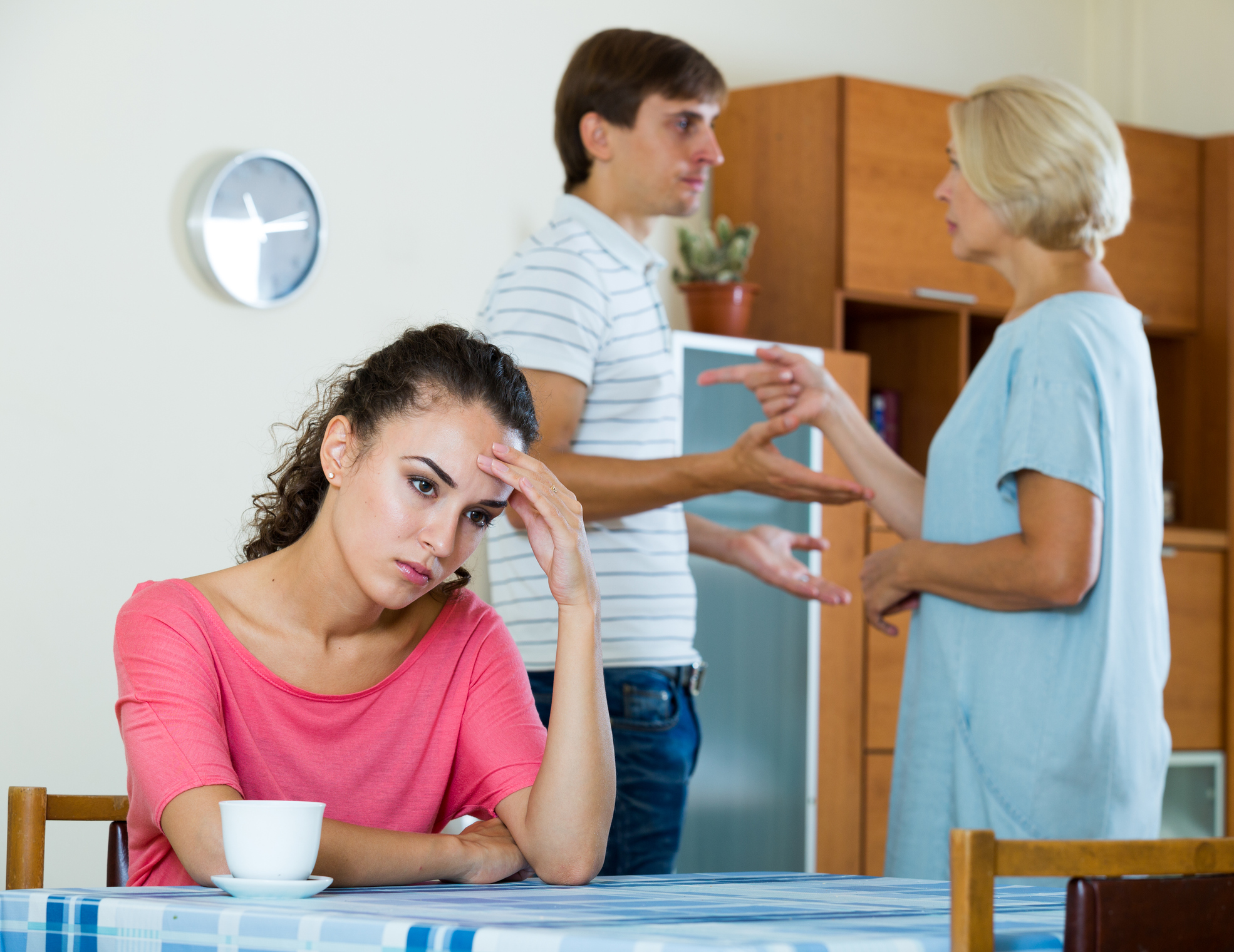 Sad young woman watching husband and mother having fight