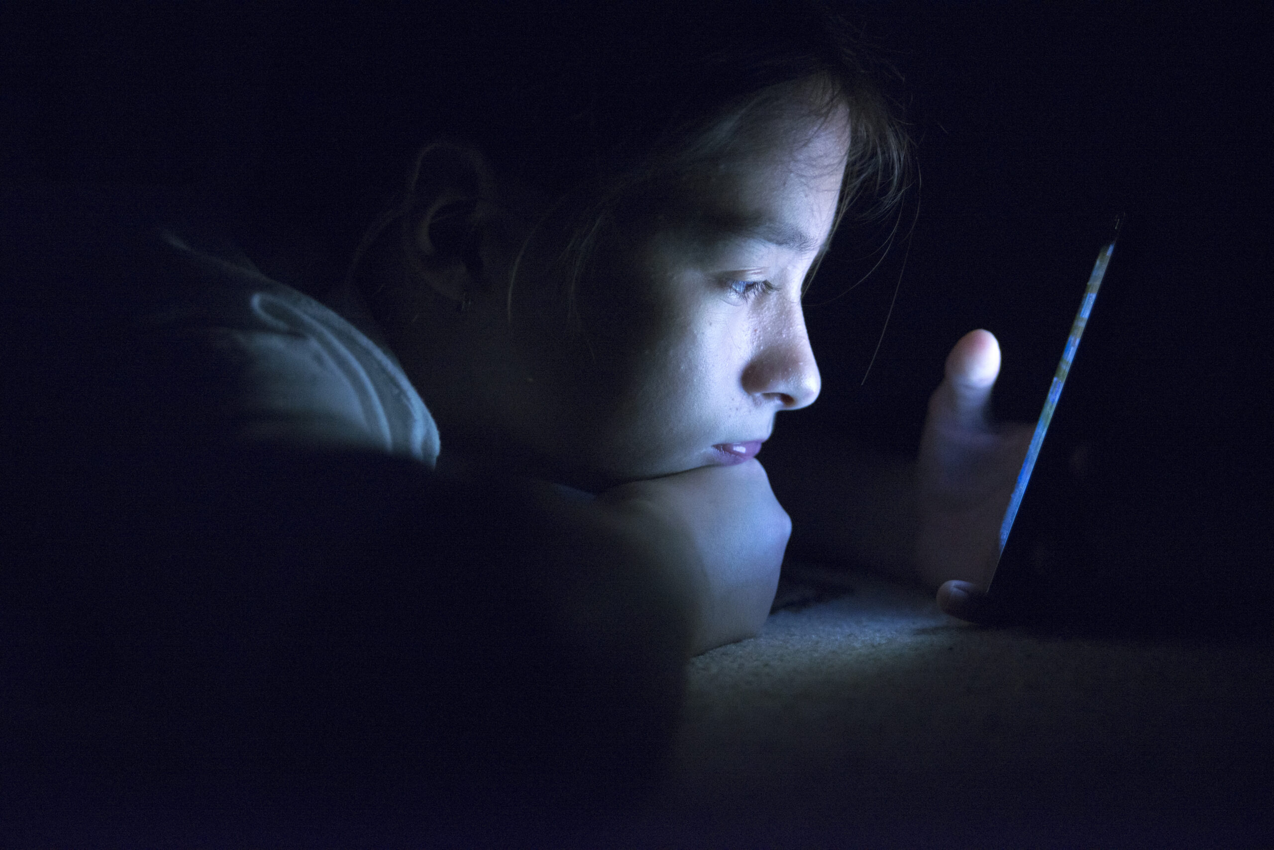 Teenager sending email from smart phone in her bed