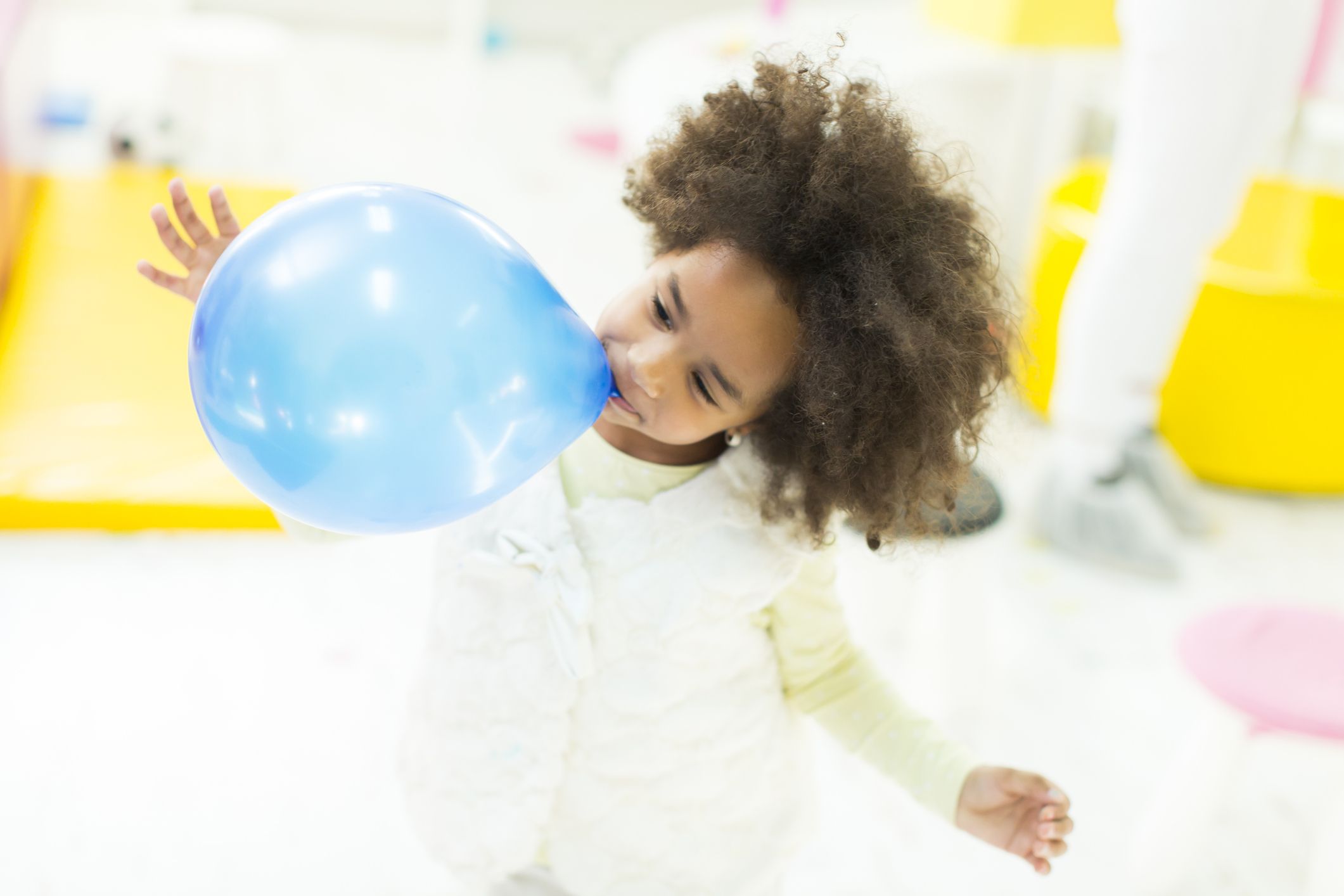 African little girl inflates blue  balloon