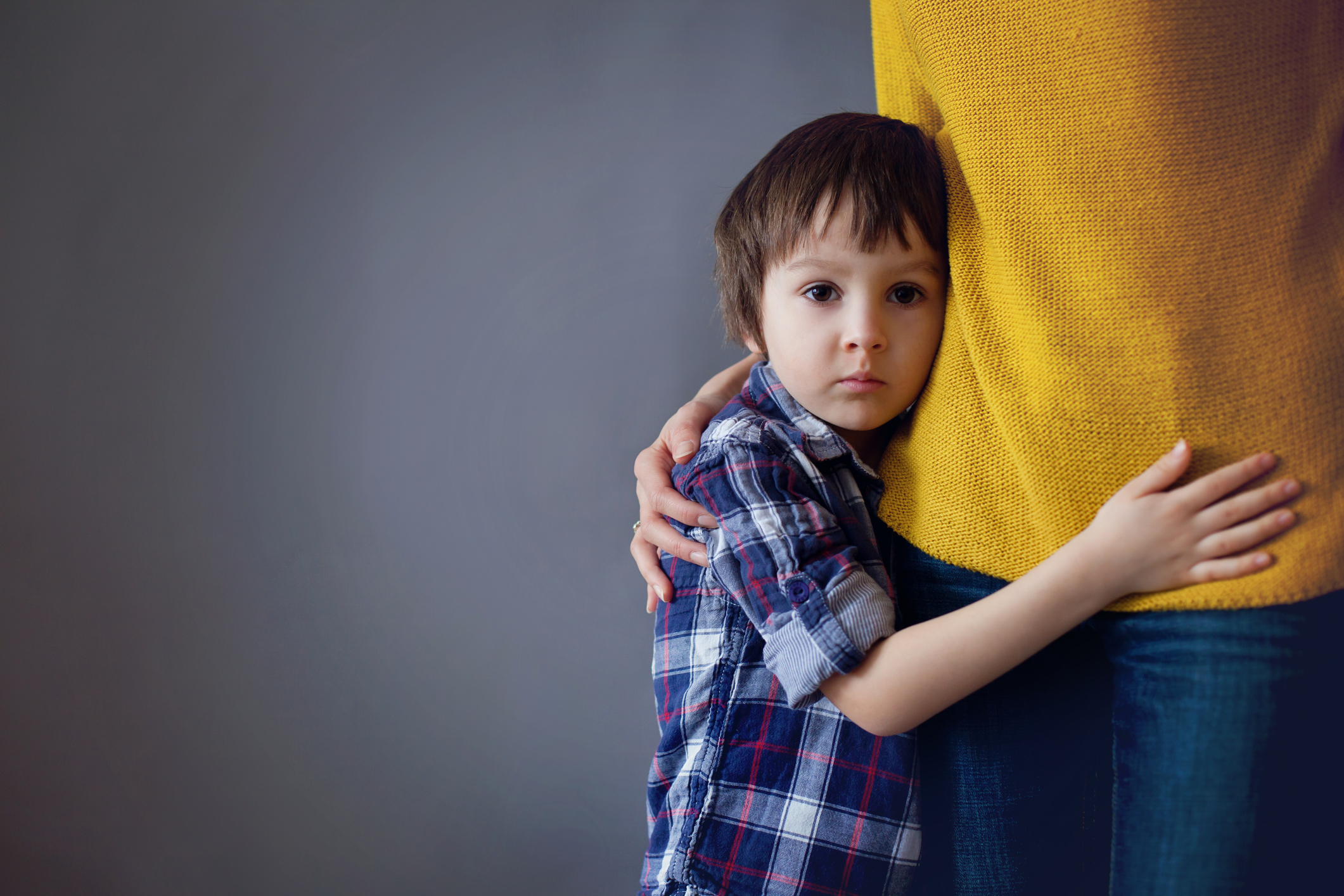 Sad little child, boy, hugging his mother at home