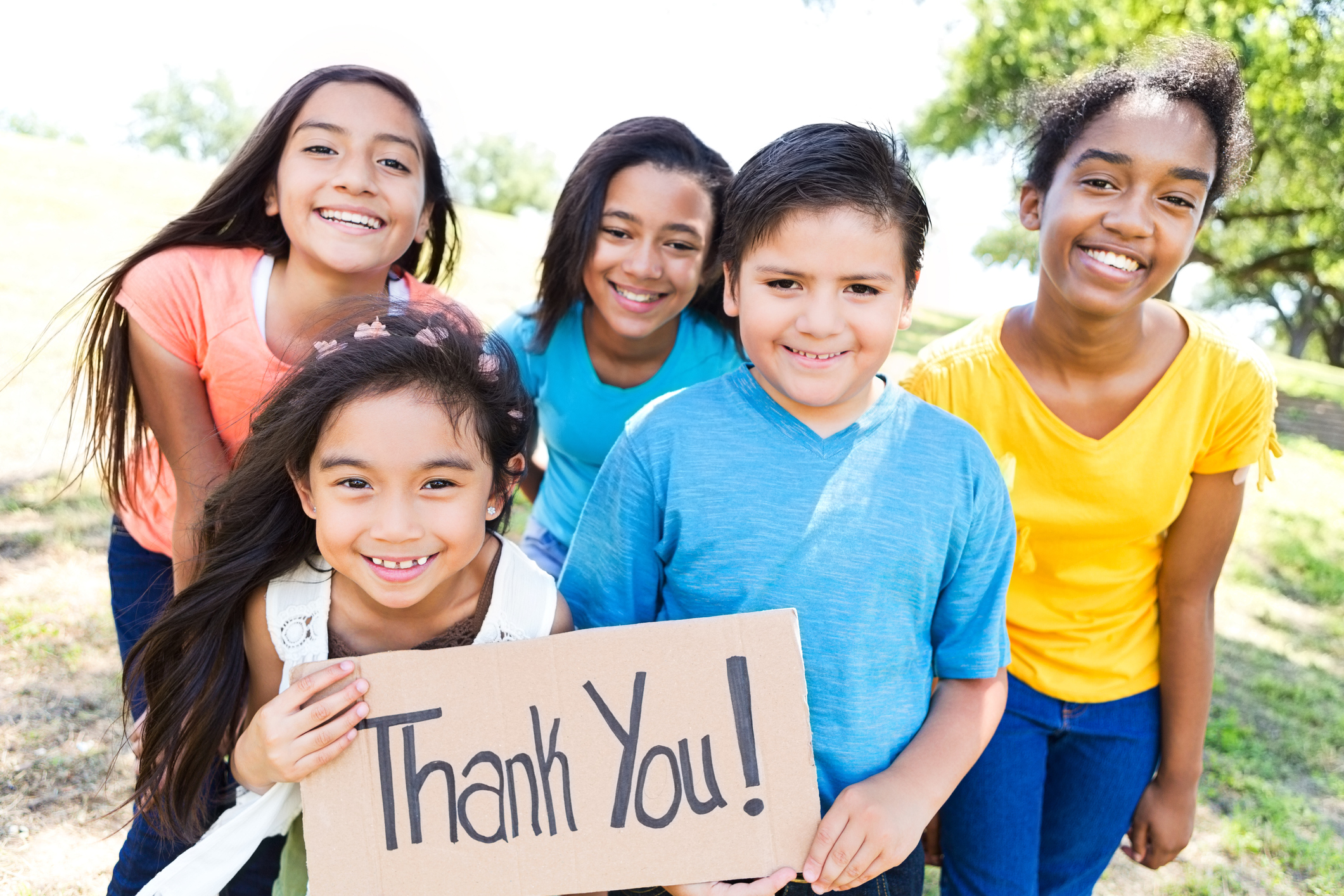 Young diverse friends in local park hold 'Thank You!' sign