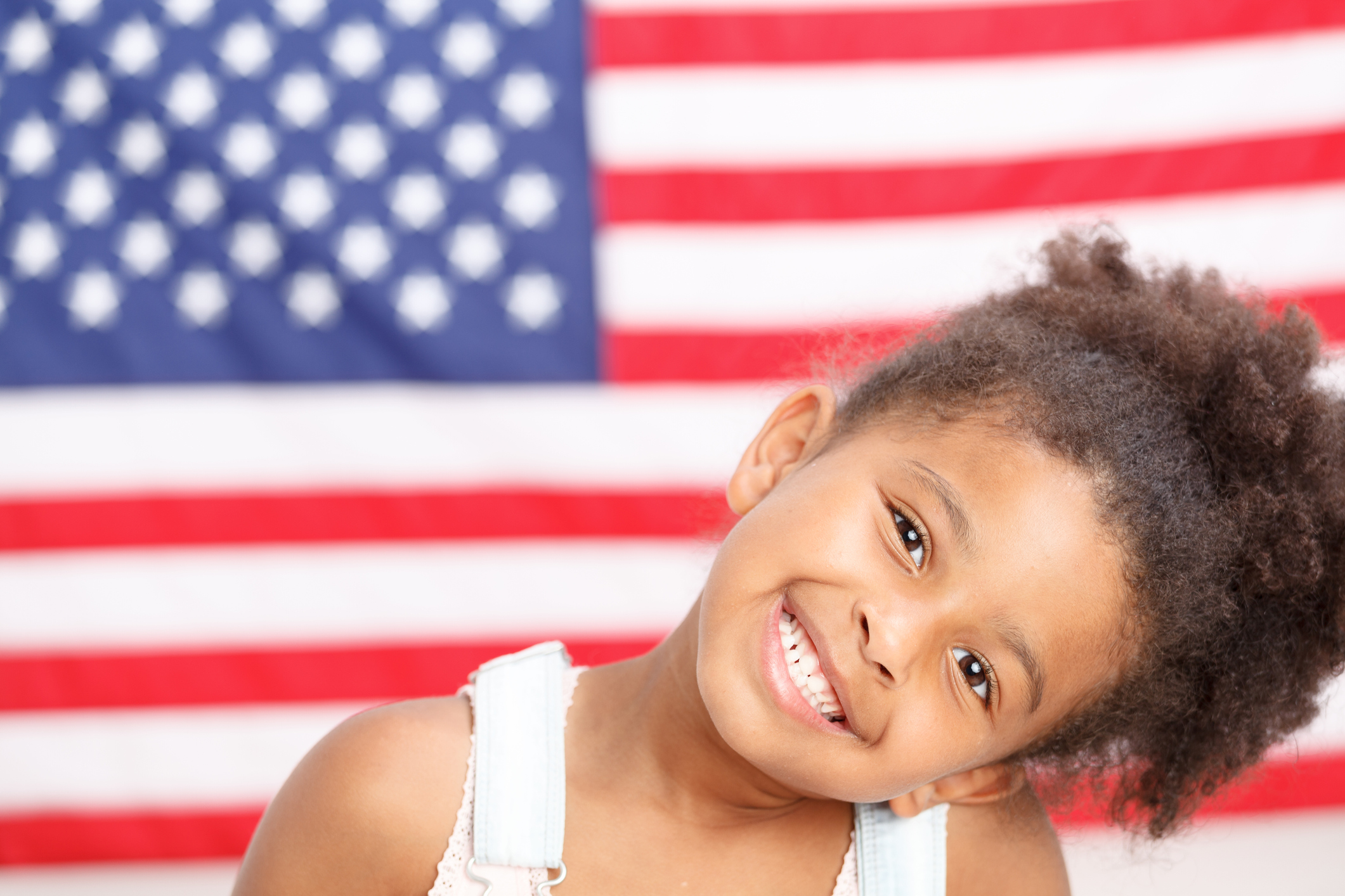 Cute preschool girl smiling in front of USA flag