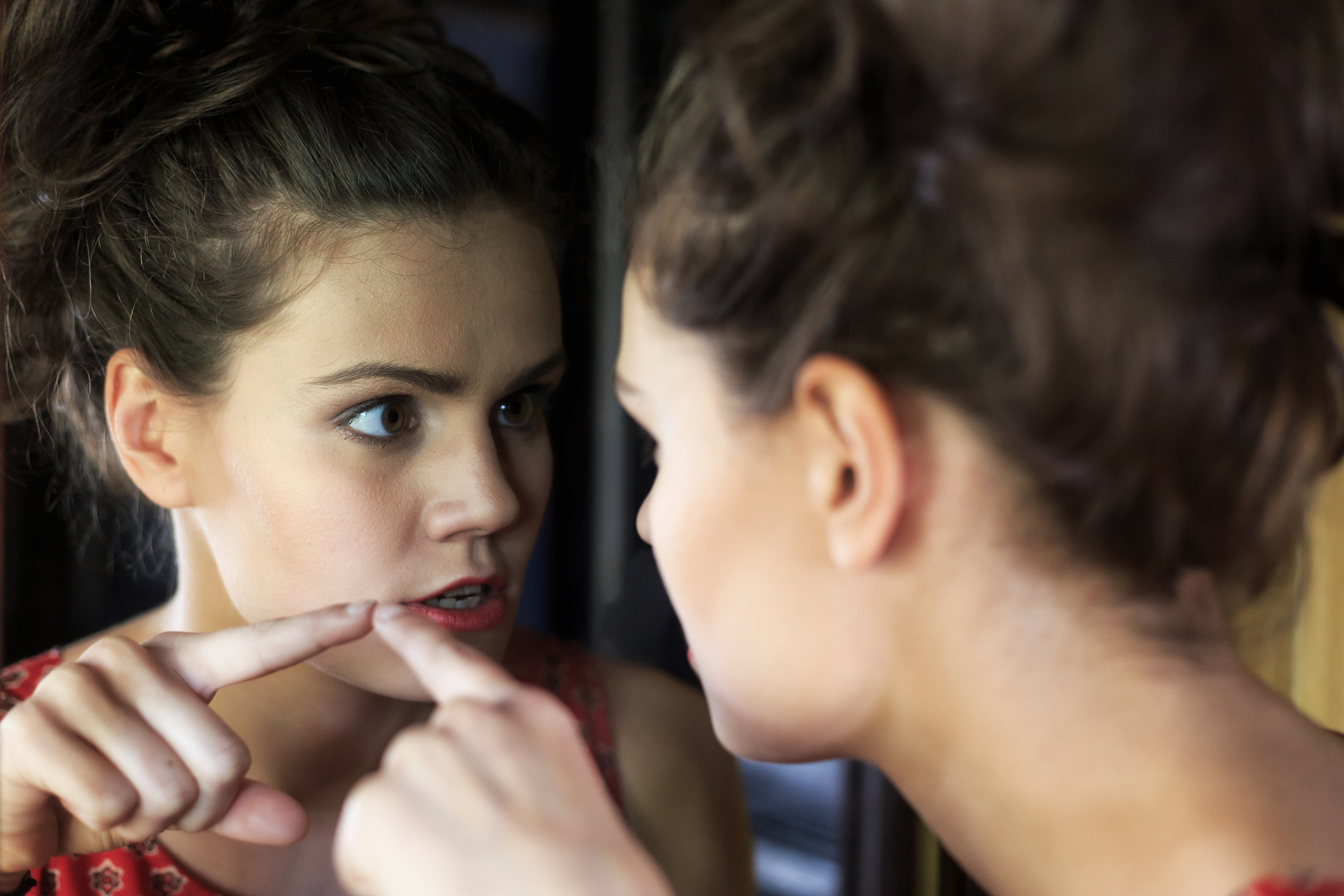 Young woman pointing at her reflection in the mirror