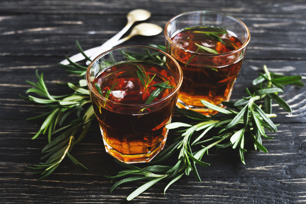 Cold rosemary tea with ice on wooden table