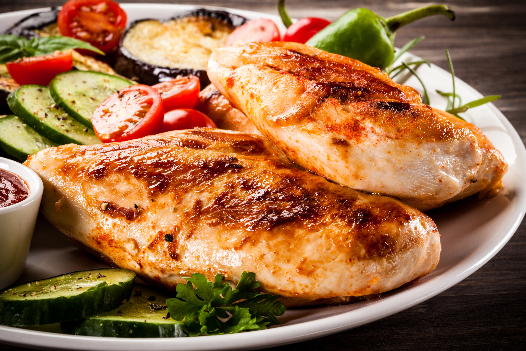 Fried chicken fillets and vegetables on wooden background