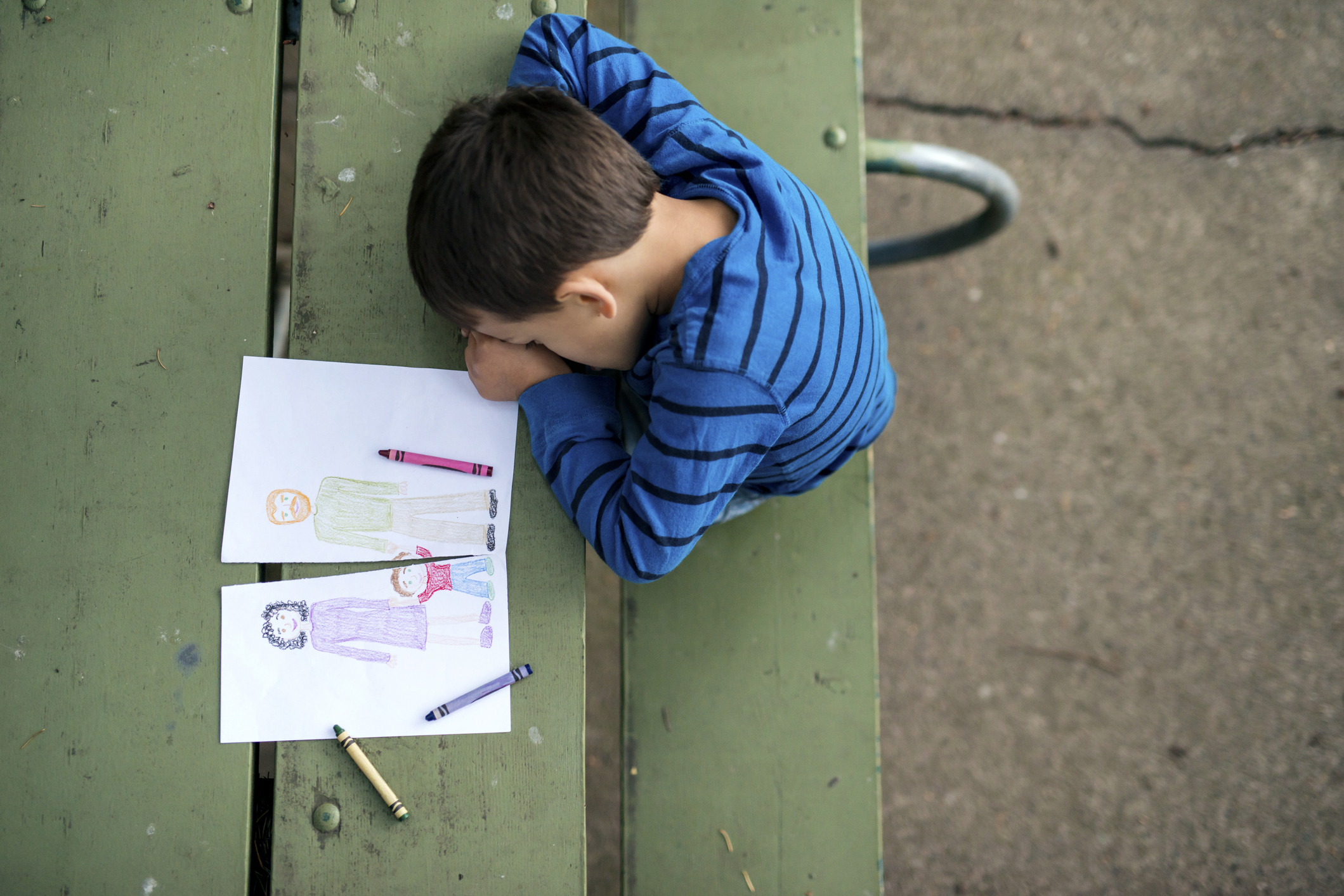 Young boy looking sad at drawing of a broken family