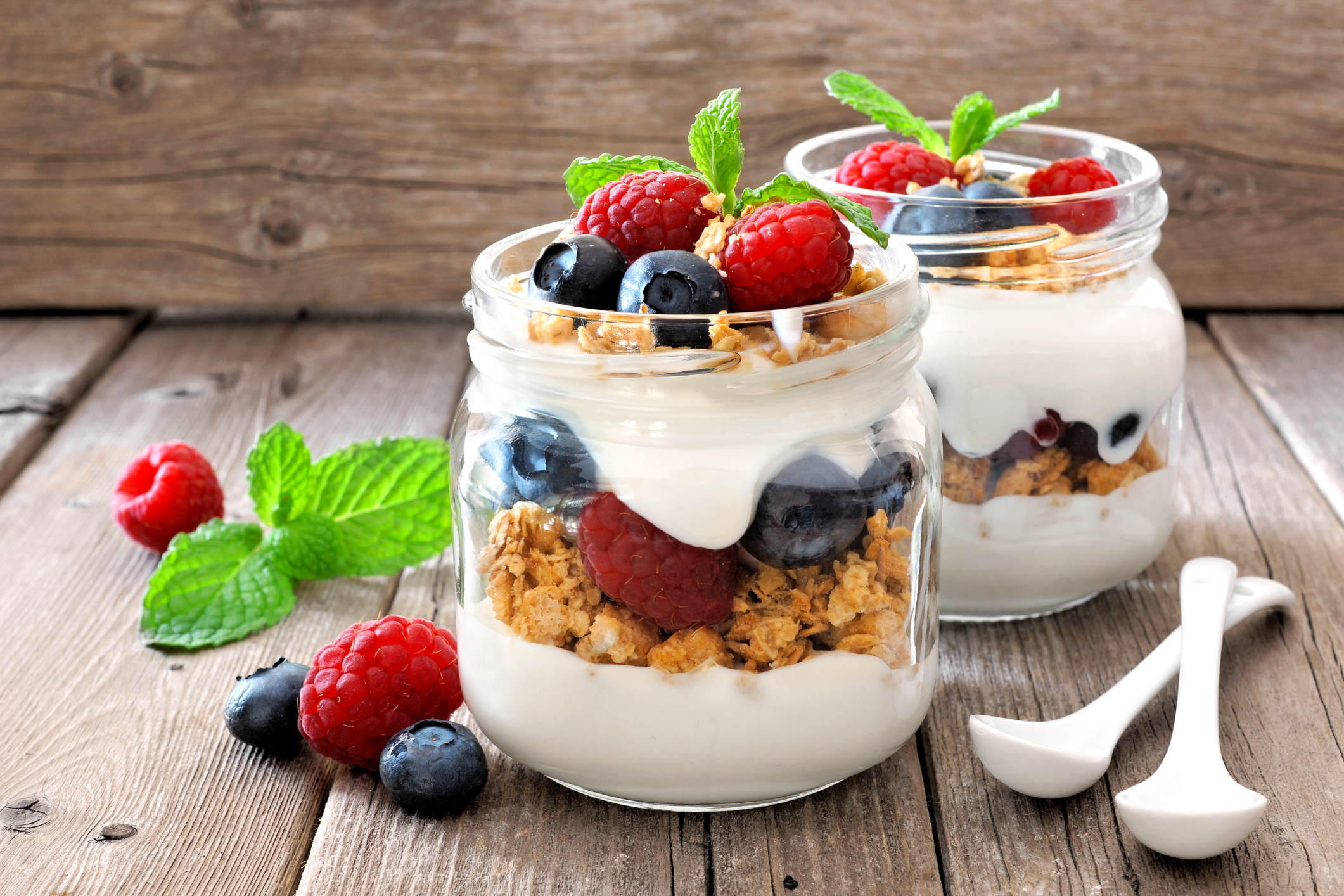 Blueberry, raspberry parfaits in mason jars, still life against wood