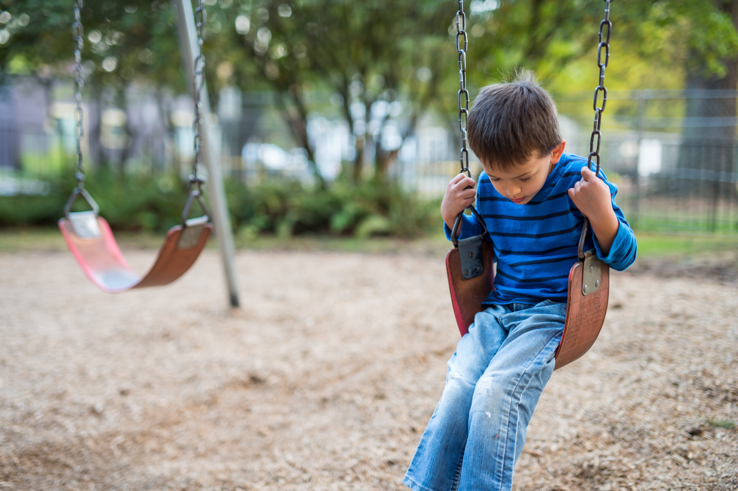 Young boy swinging by himself on playground