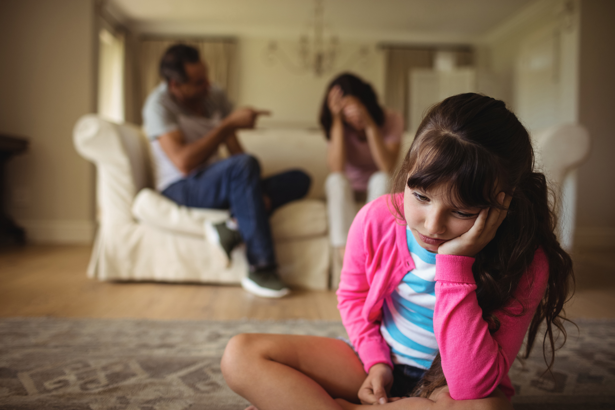 Sad girl listening to her parents arguing