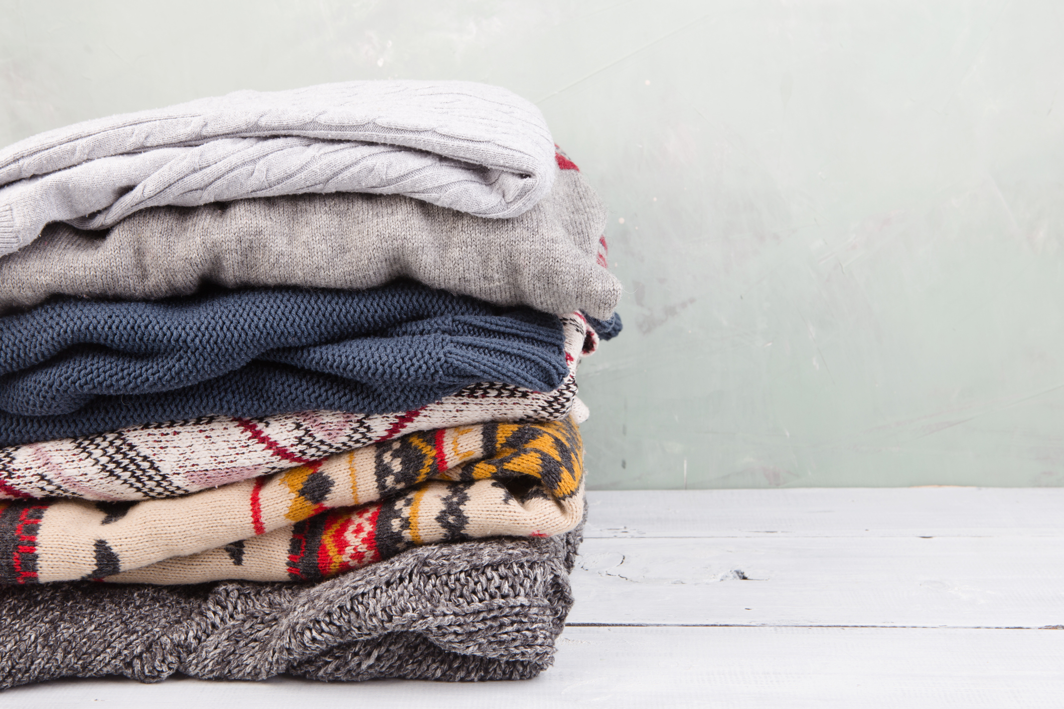 warm sweaters stacked on wooden table