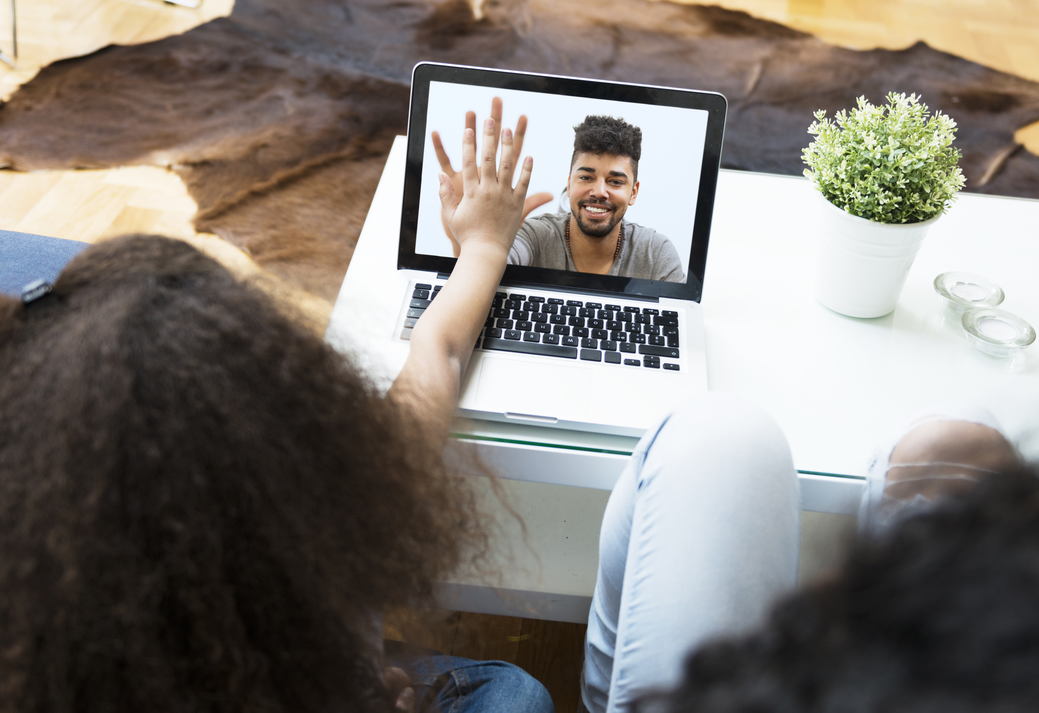 Child video chatting over a laptop with her father