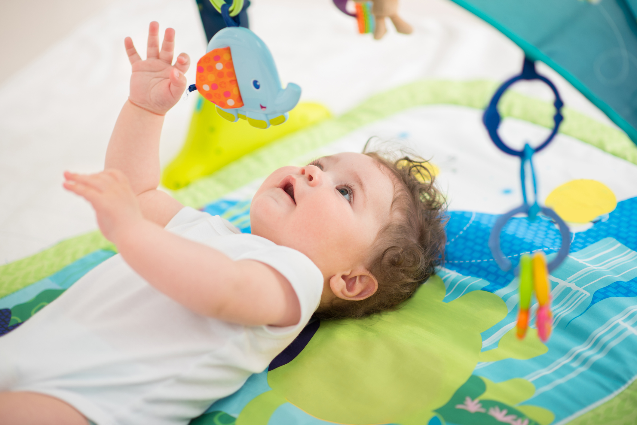 Baby Boy lying on back and playing with toys