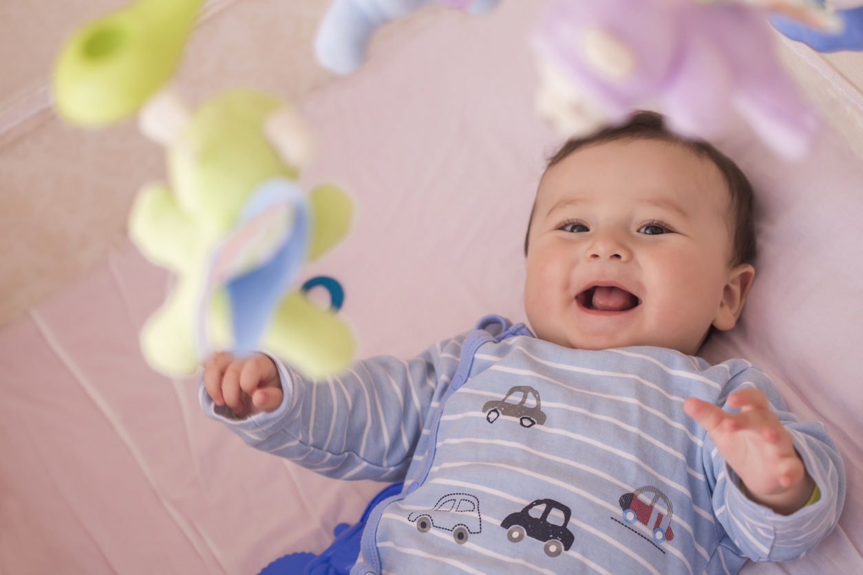 Happy baby lying in his crib smiling