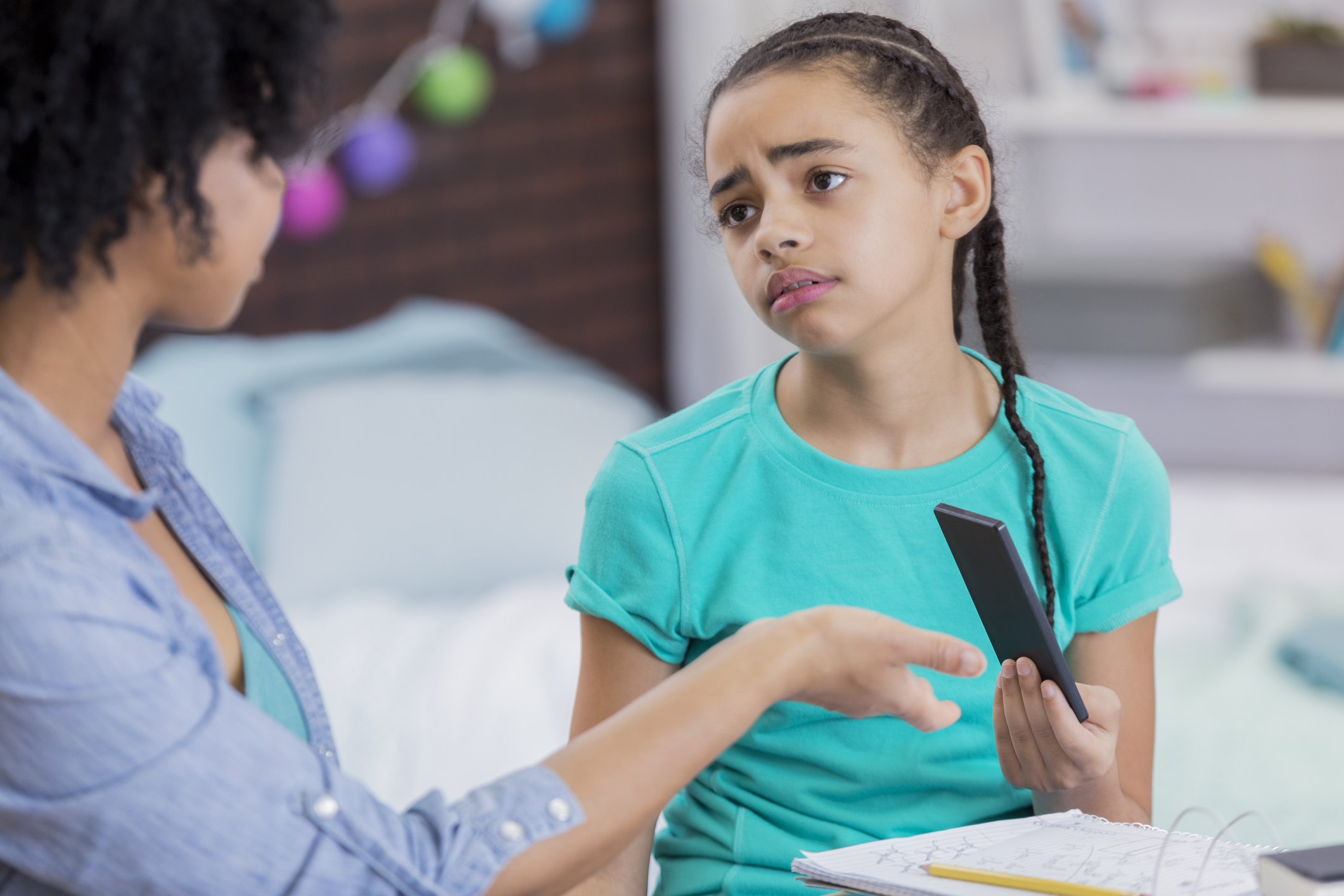 Tween girl hands her phone over to her mother