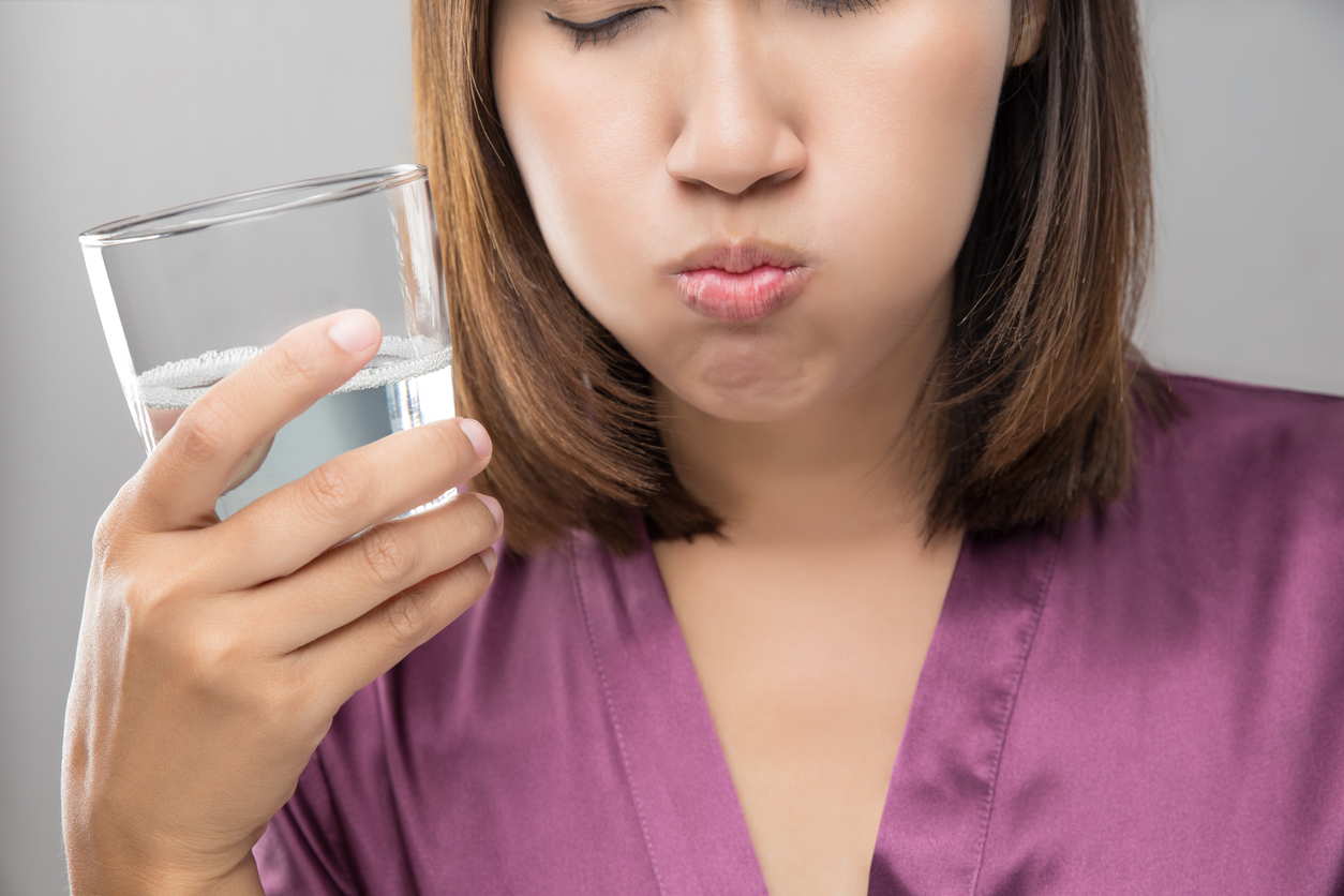 Woman rinsing and gargling while using mouthwash from a glass, During daily oral hygiene routine, Girl in a purple silk robe, Dental Healthcare Concepts