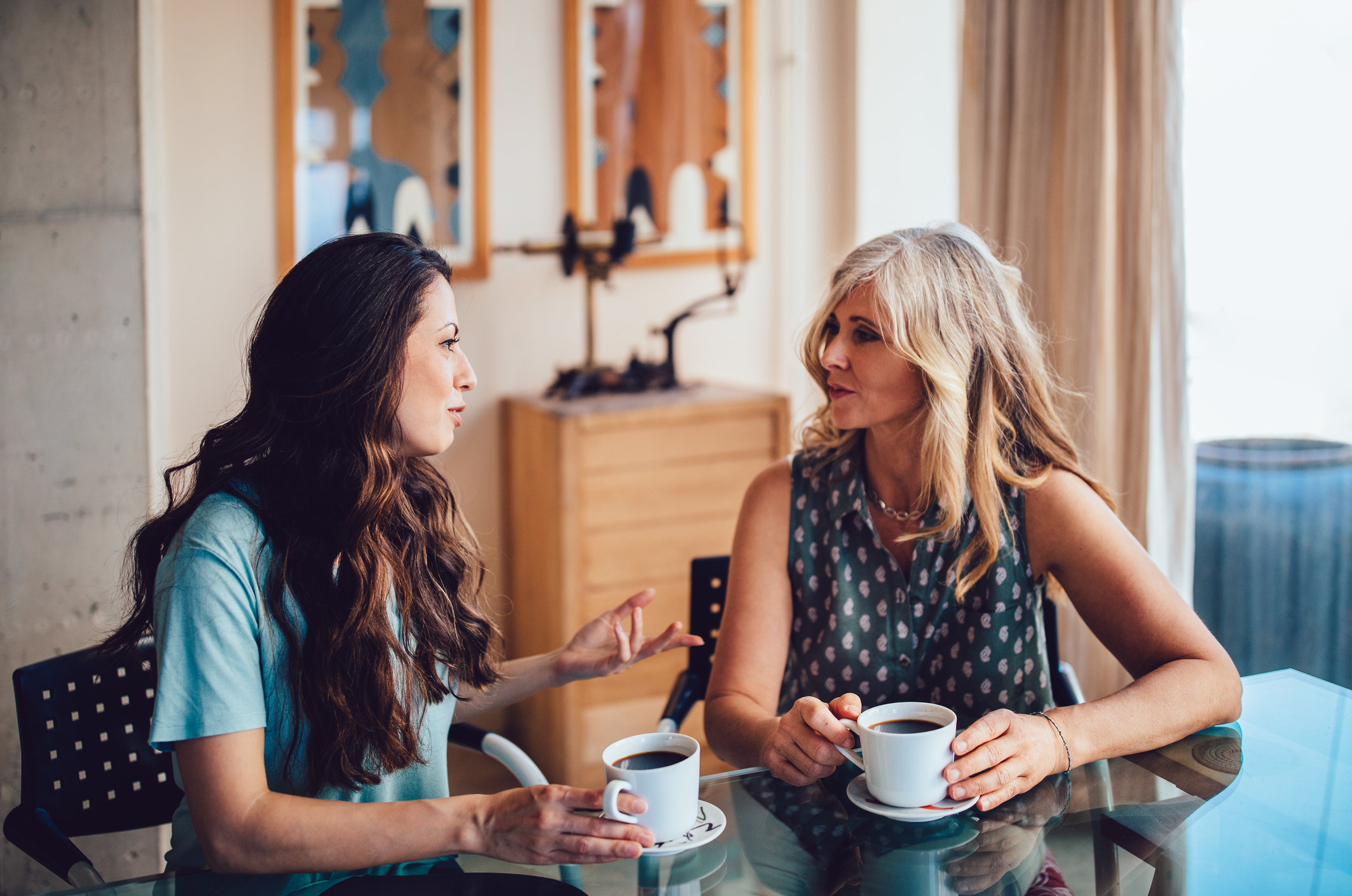 Senior mother and daughter drinking coffee together at home