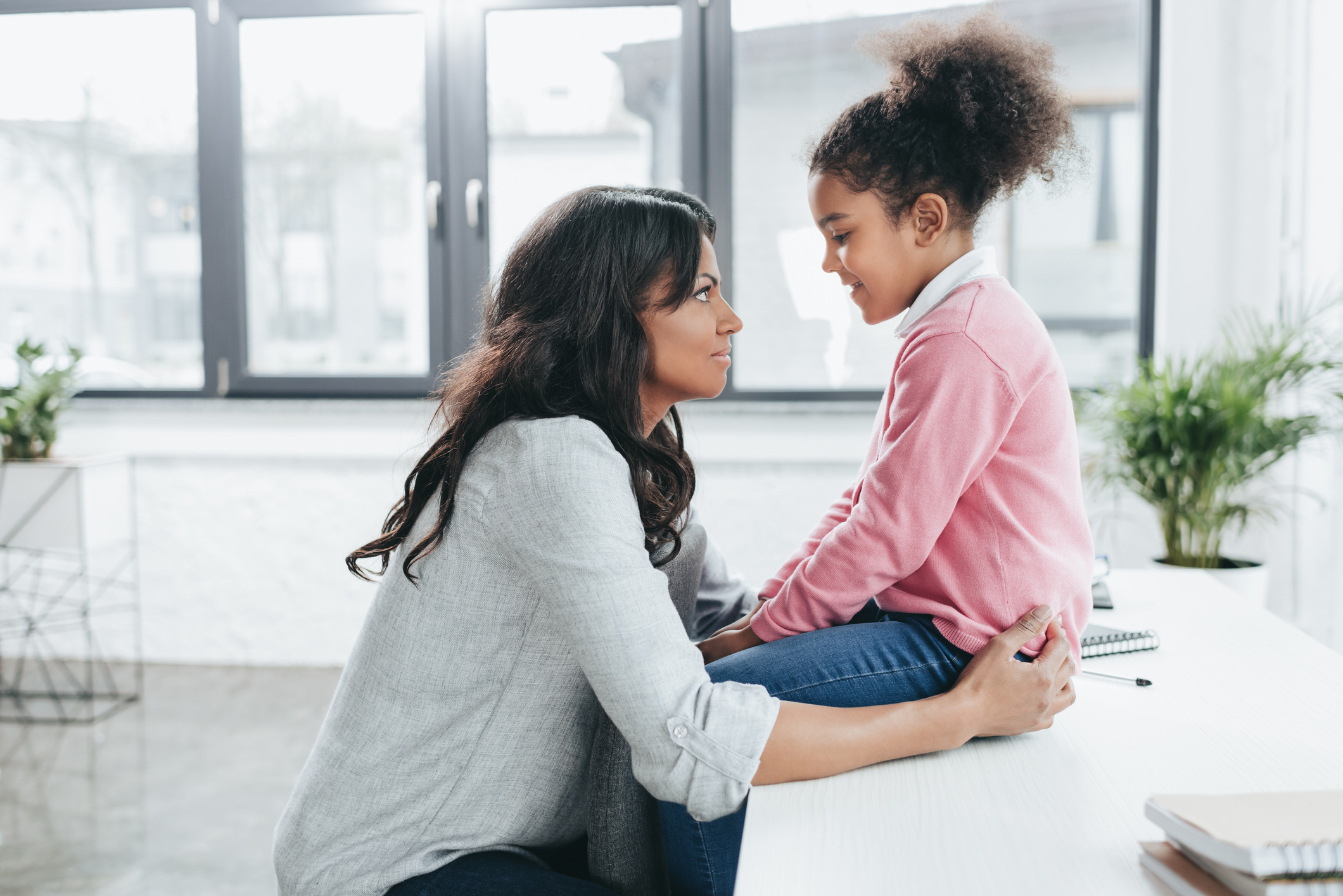 side view of african american mother talking with her daughter indoors