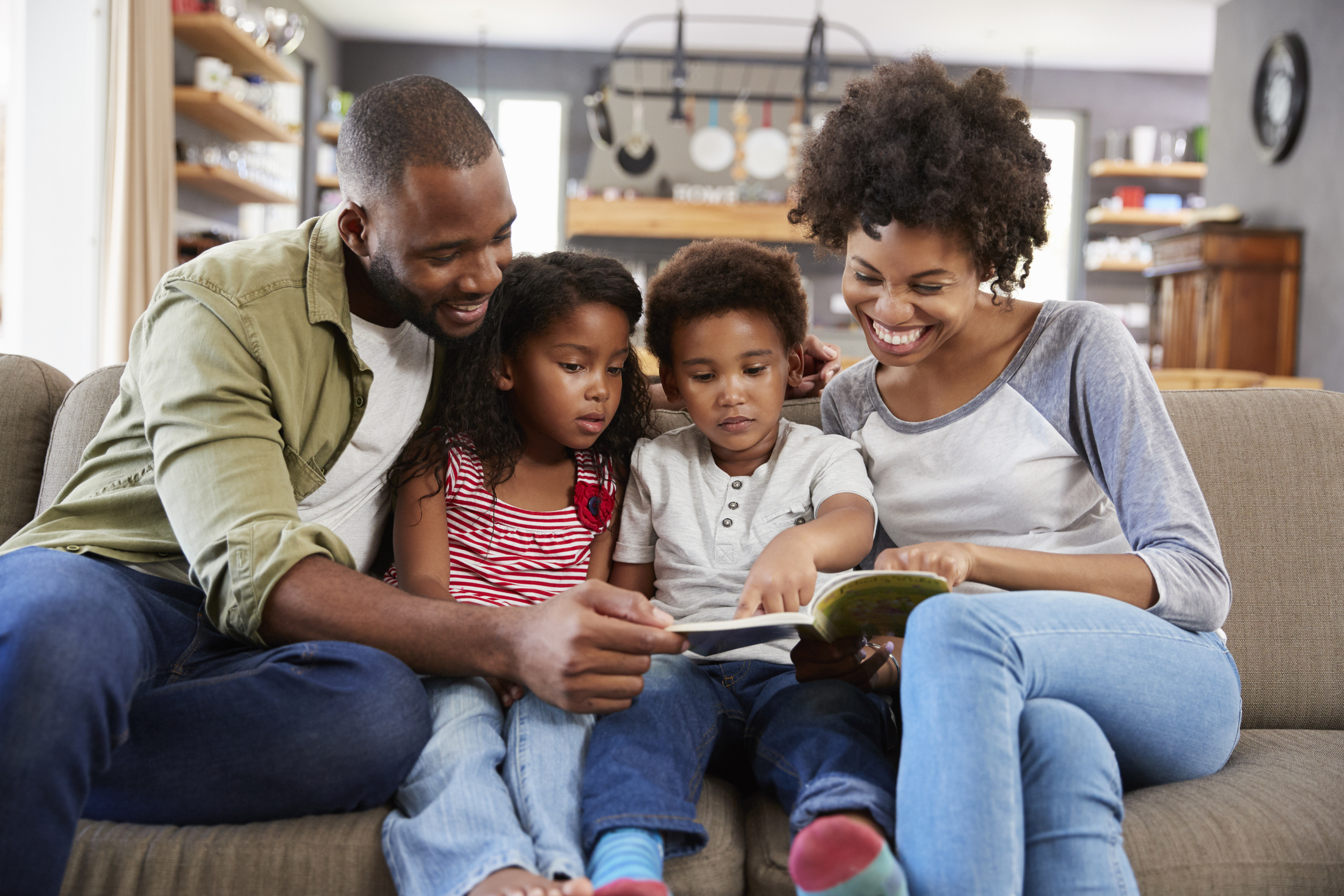 Family Sitting On Sofa In Lounge Reading Book Together