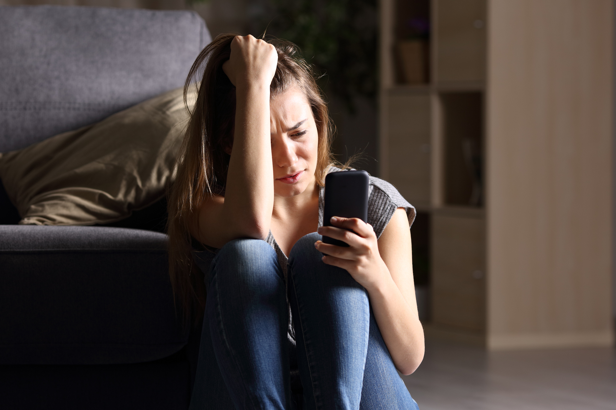 Sad teen checking phone at home