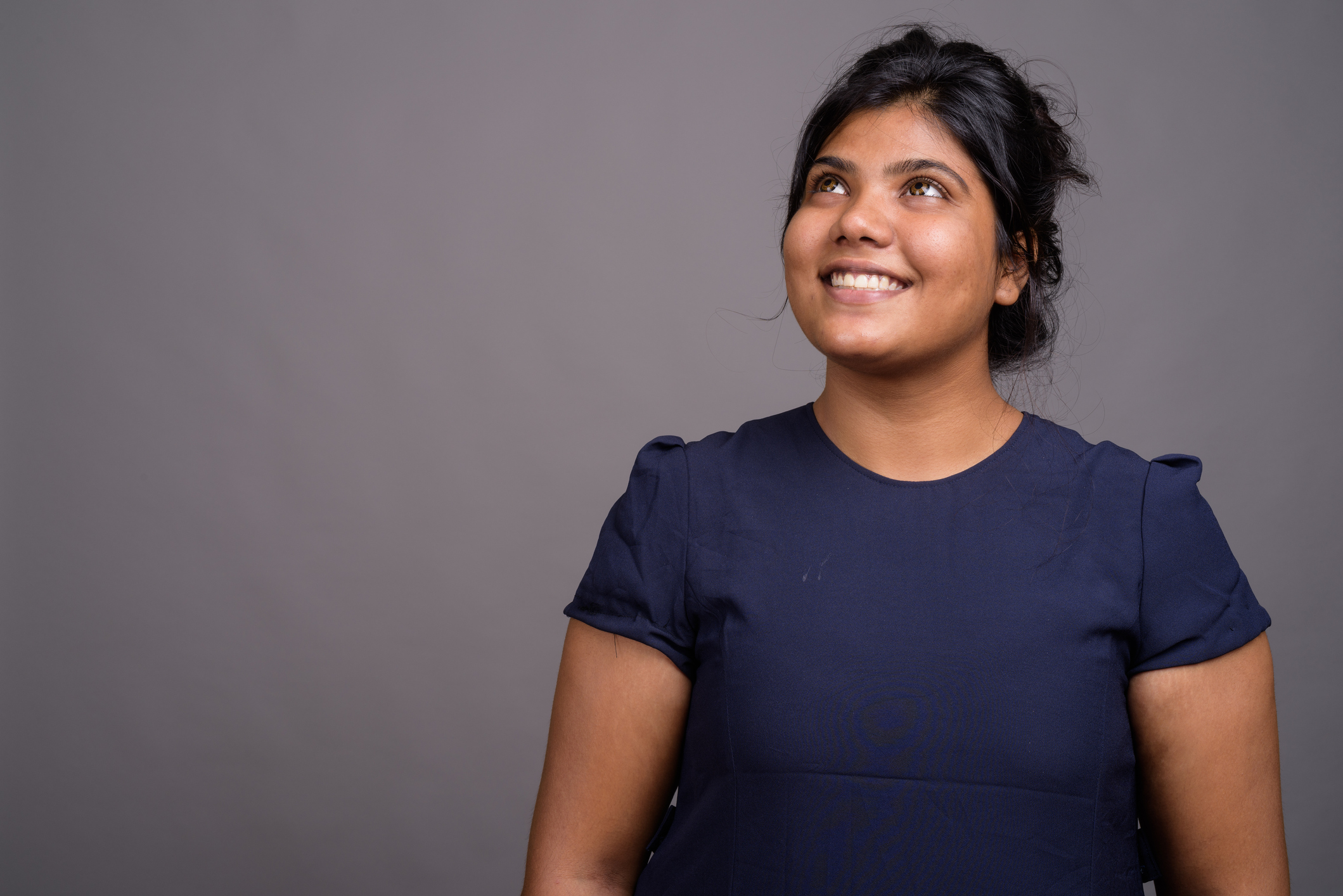 Studio shot of young overweight beautiful Indian woman against gray background