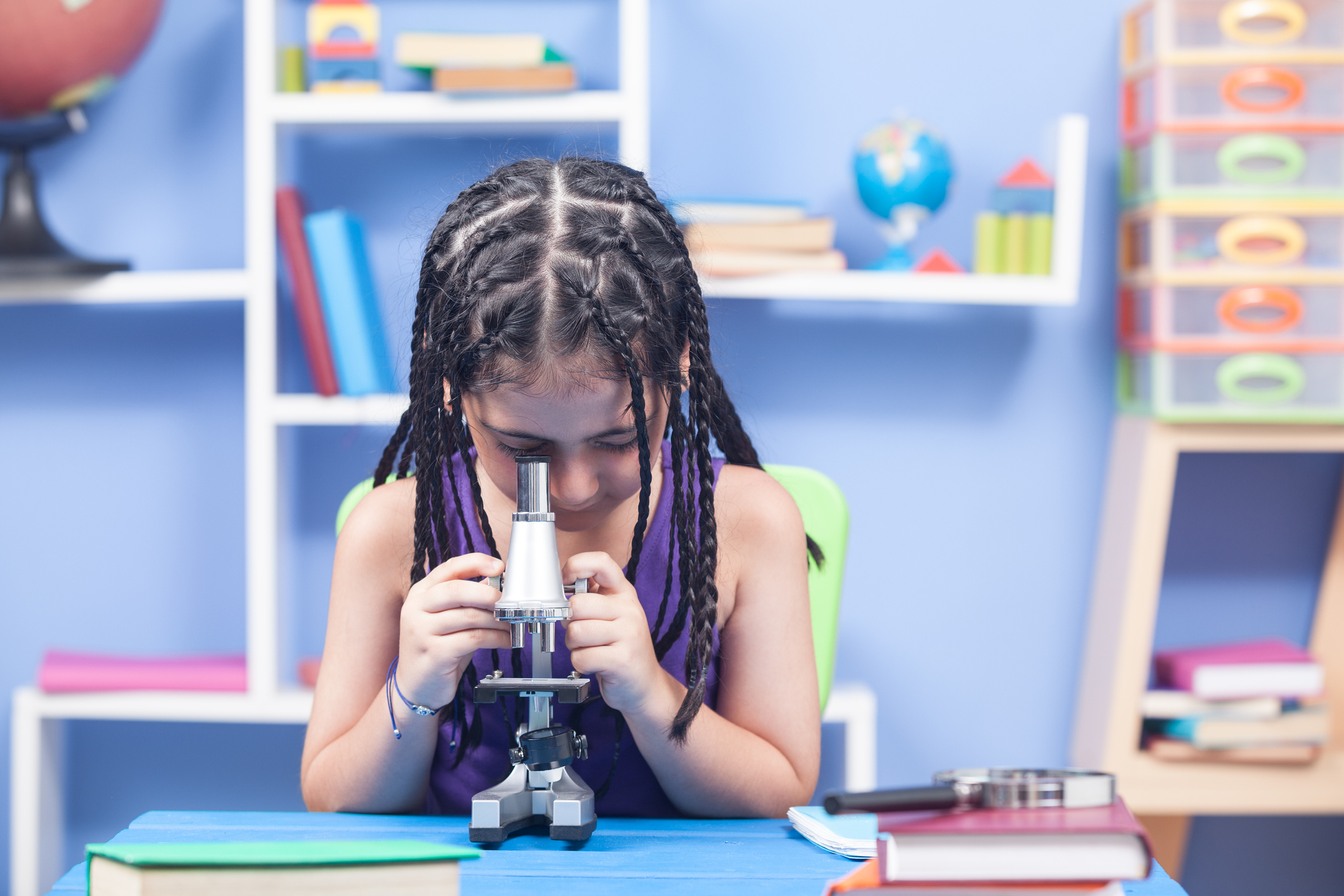 Little Elementary Schoolgirl Using Microscope In Classroom