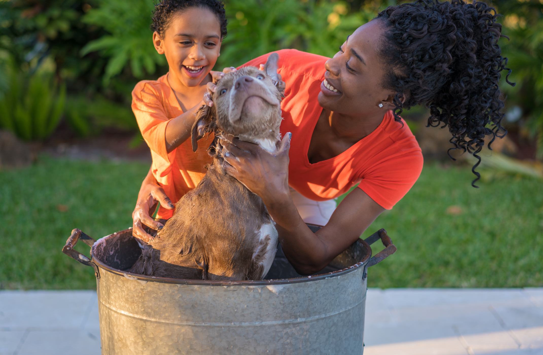 Mother and son bathing dog