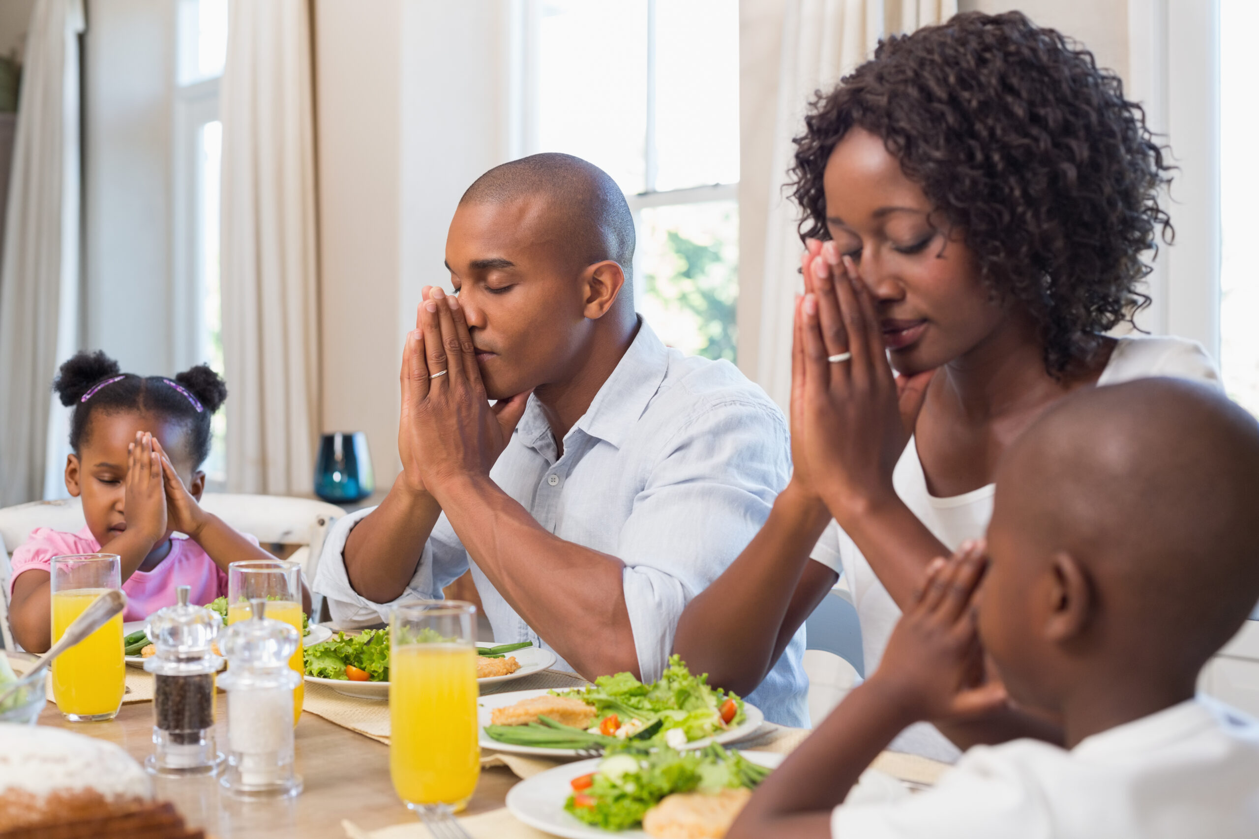 Happy family saying grace before meal