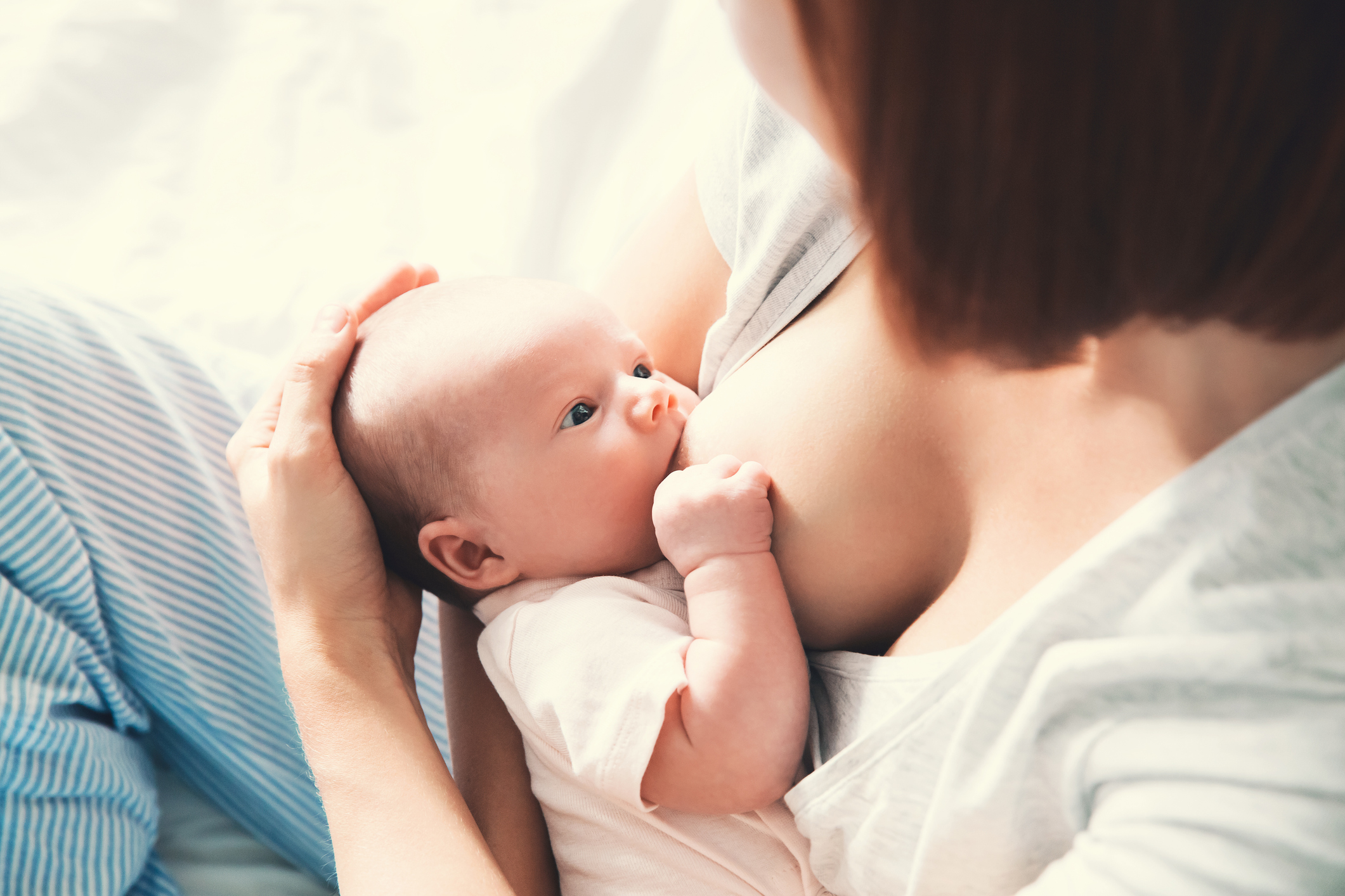 Mother breastfeeding baby in her arms at home.