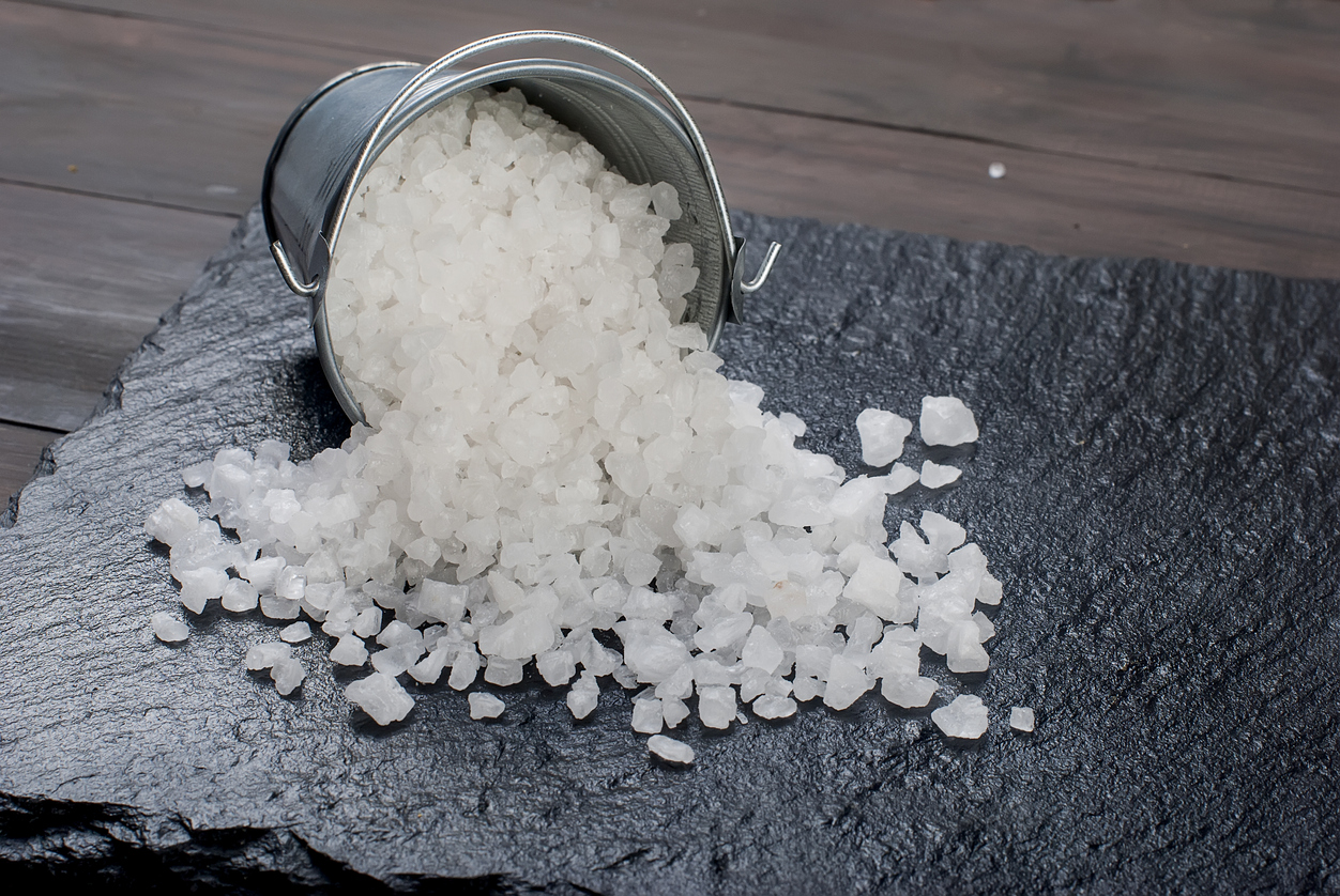 Large sea salt in a bucket on a stone background