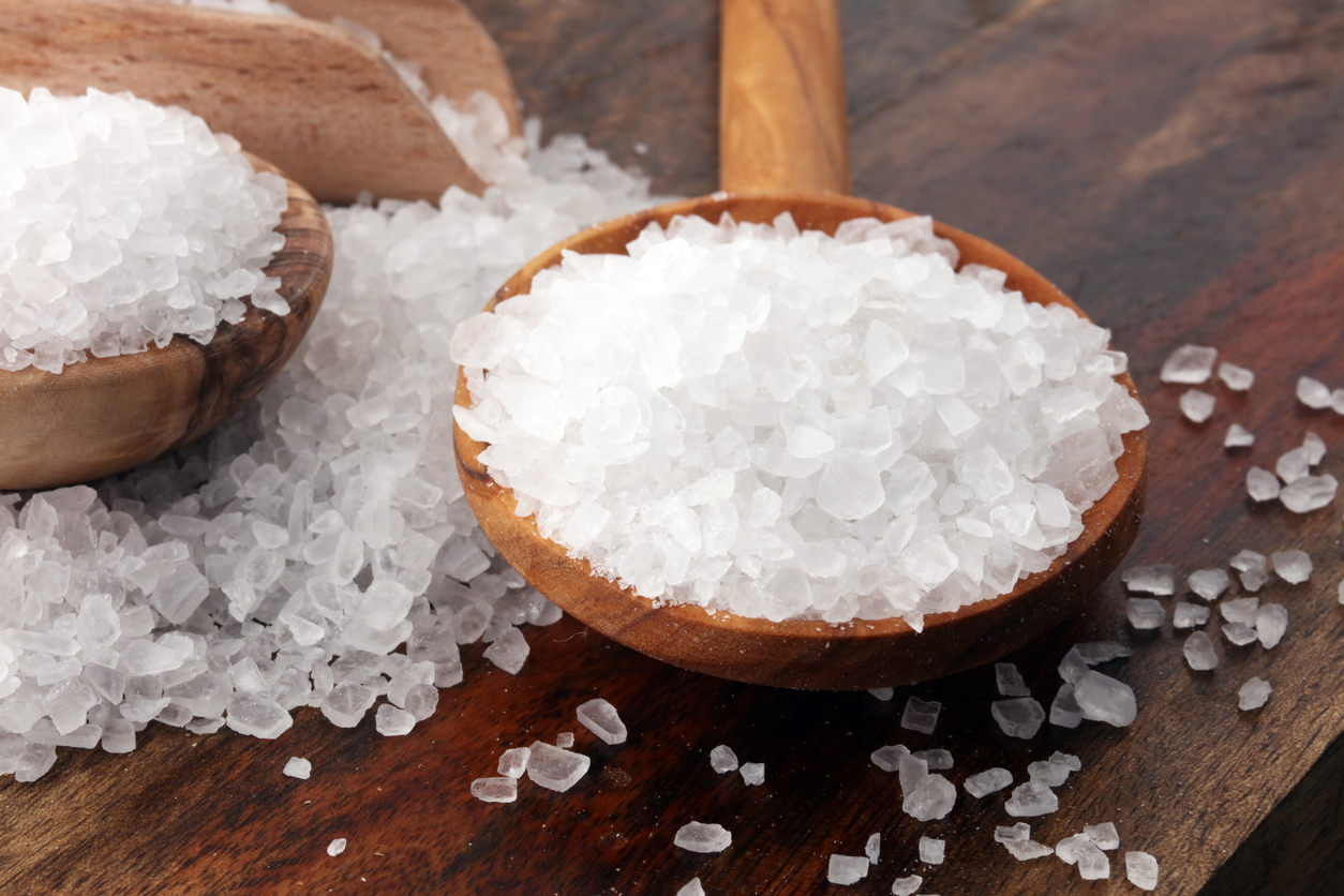 sea salt with wooden spoon and crystals of salt on wooden background