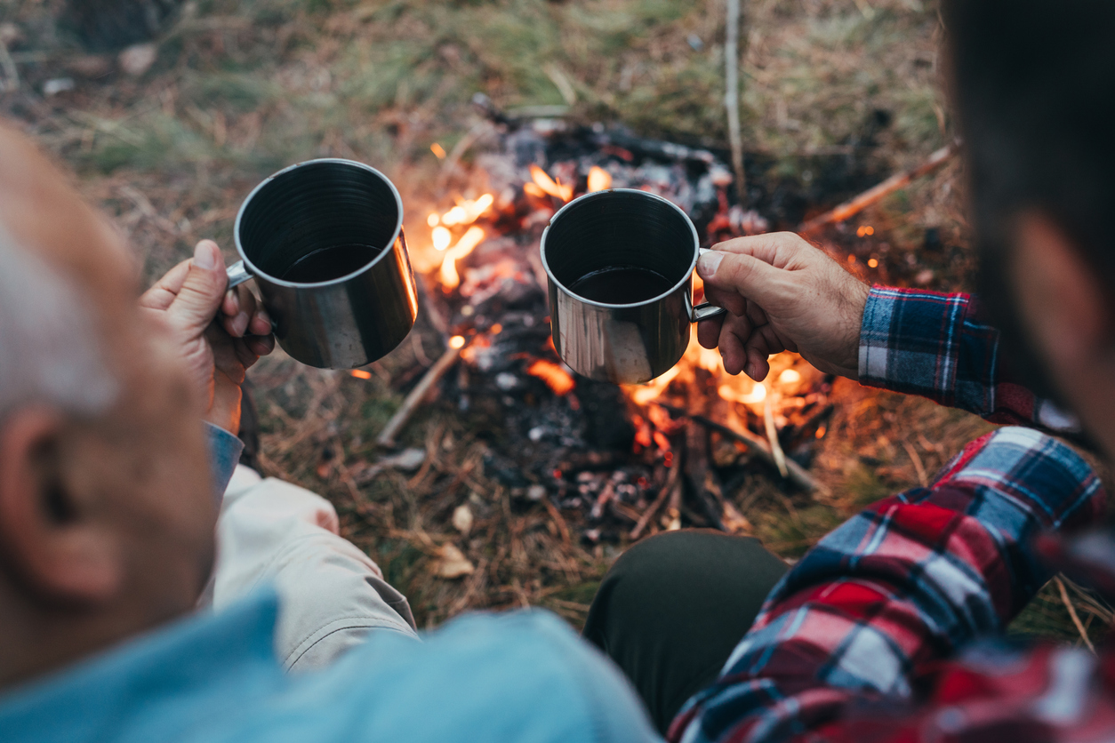 Drinking coffee near fire in nature