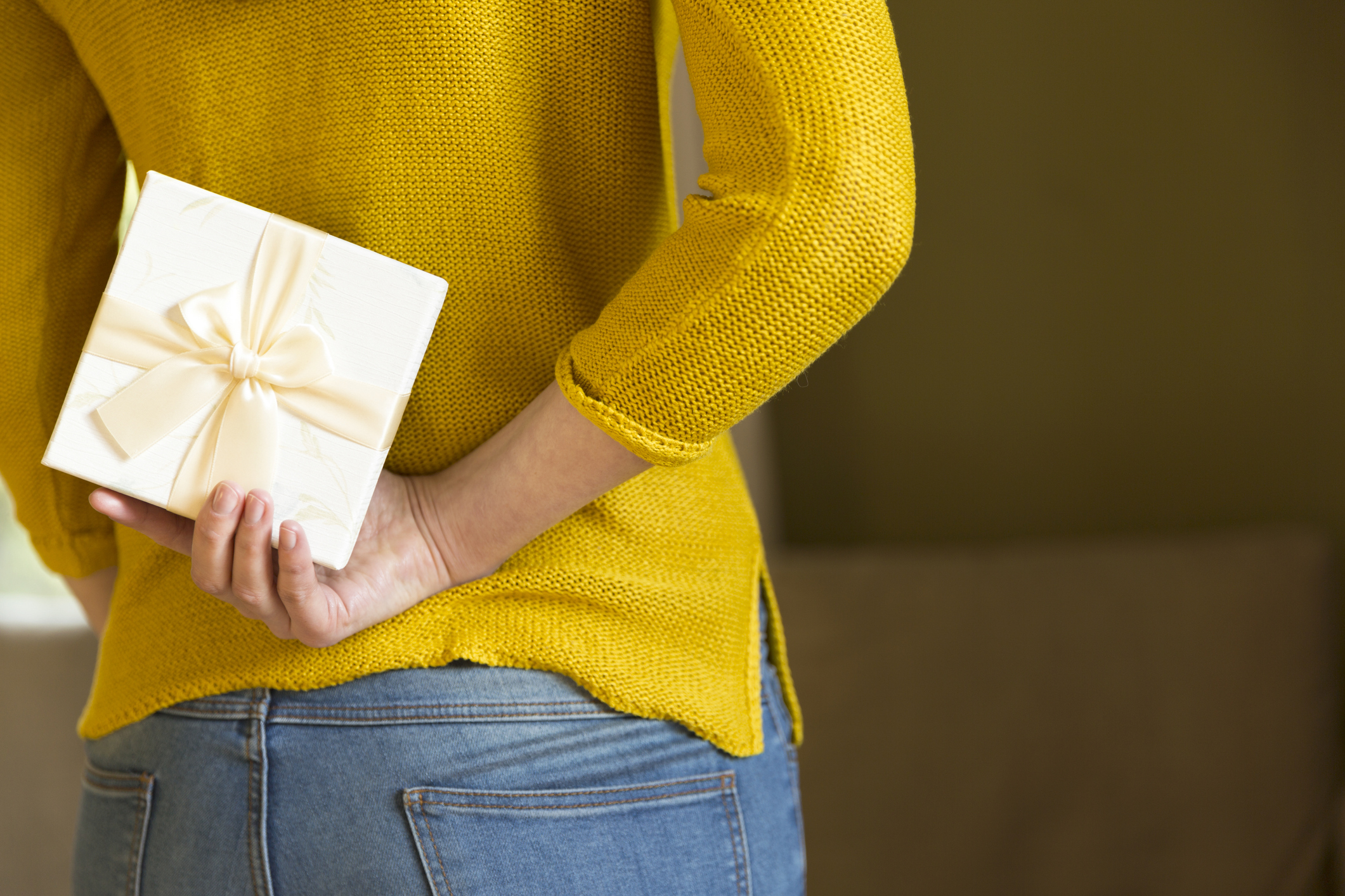 Woman hiding gift box behind her back