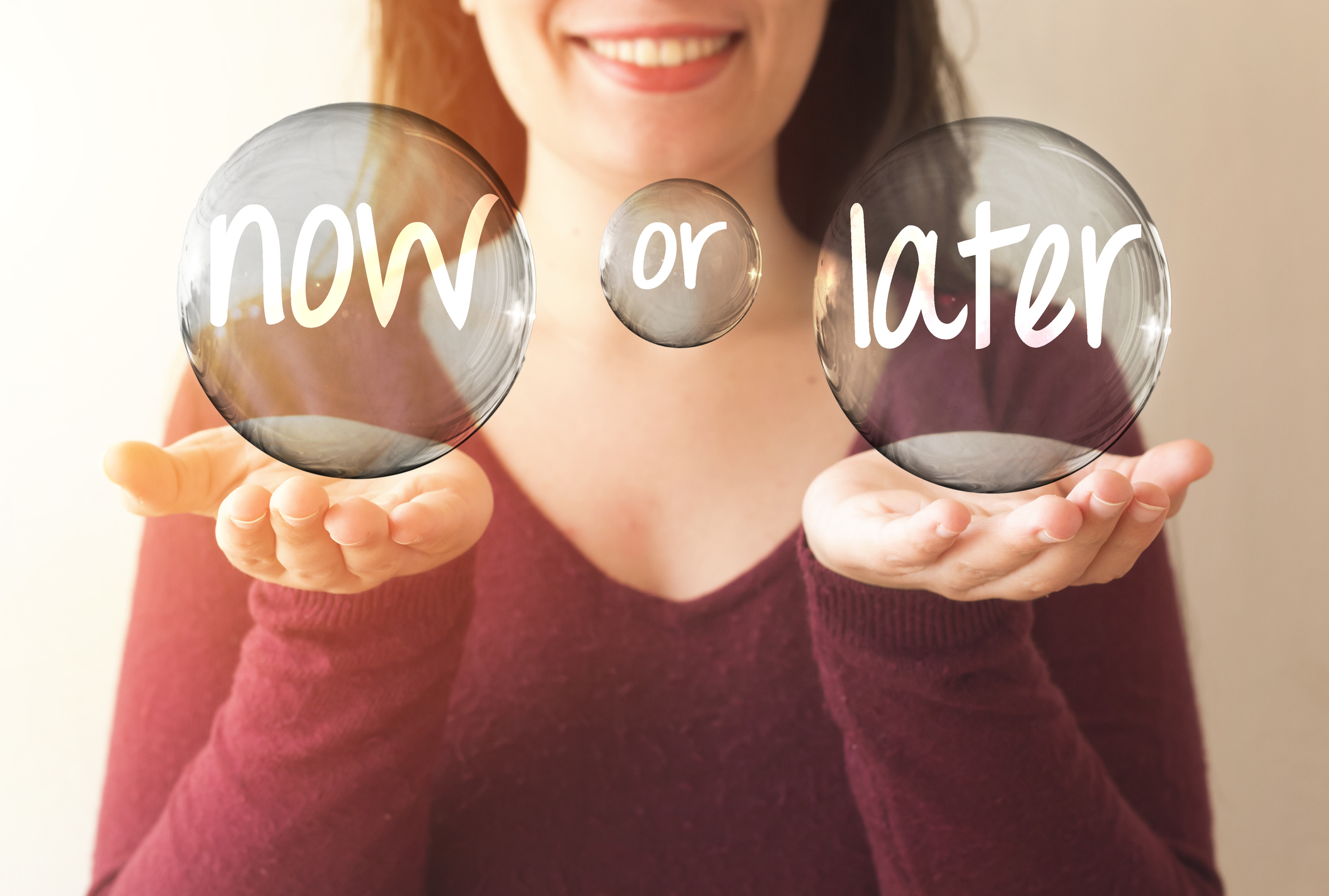 business woman holding transparent bubble with now or later text