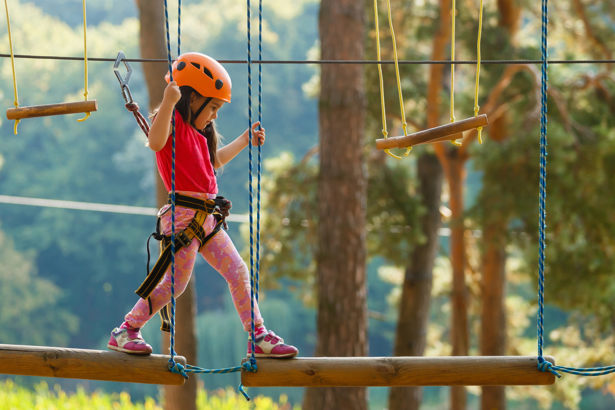 Portrait of cute little boy and girl walk on a rope bridge in an adventure rope park.